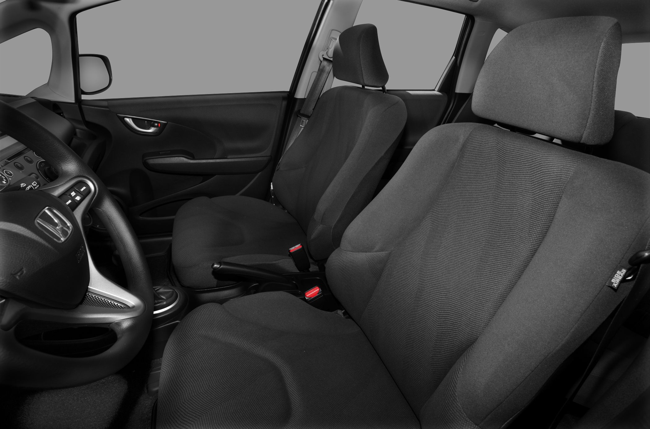 Front fabric seats with steering wheel and dashboard in compact car.
