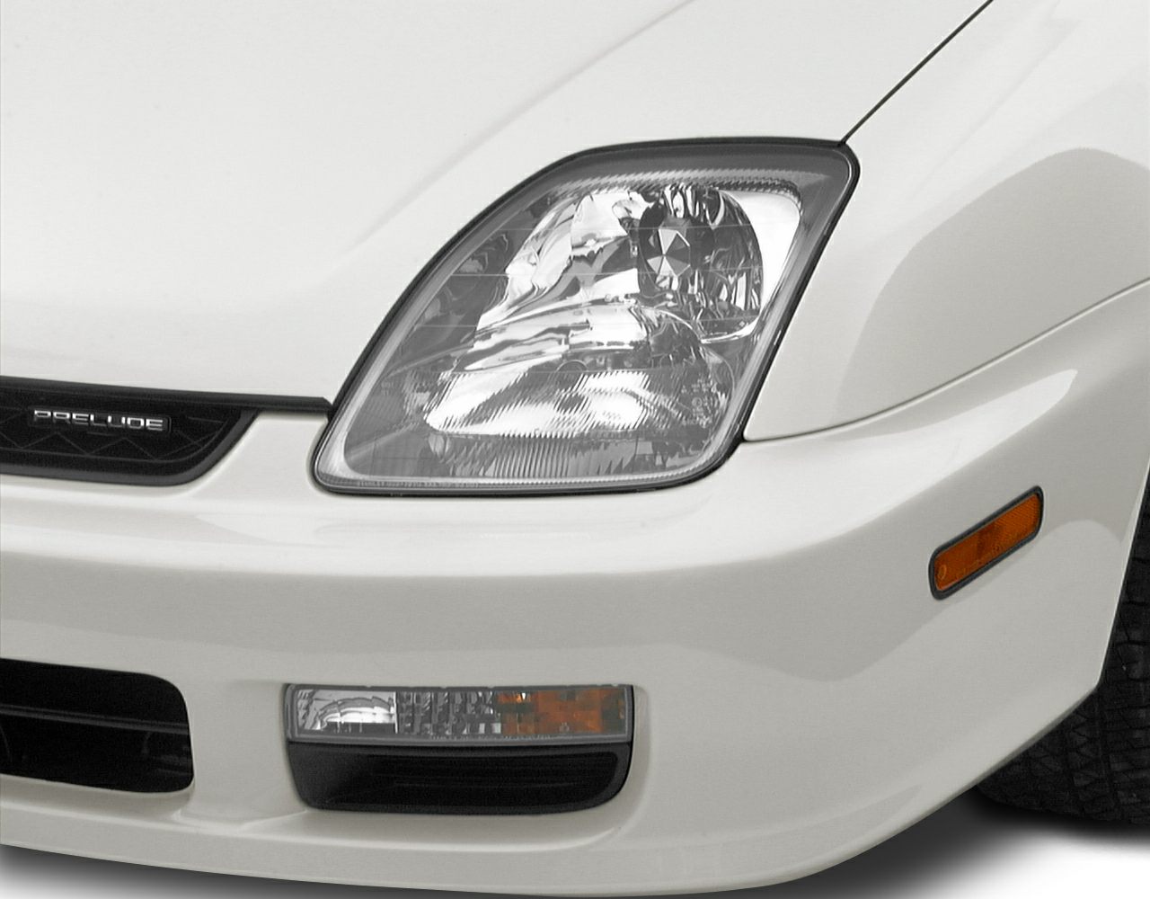 Close-up of front headlight, grille, and bumper with turn signal and fog light
