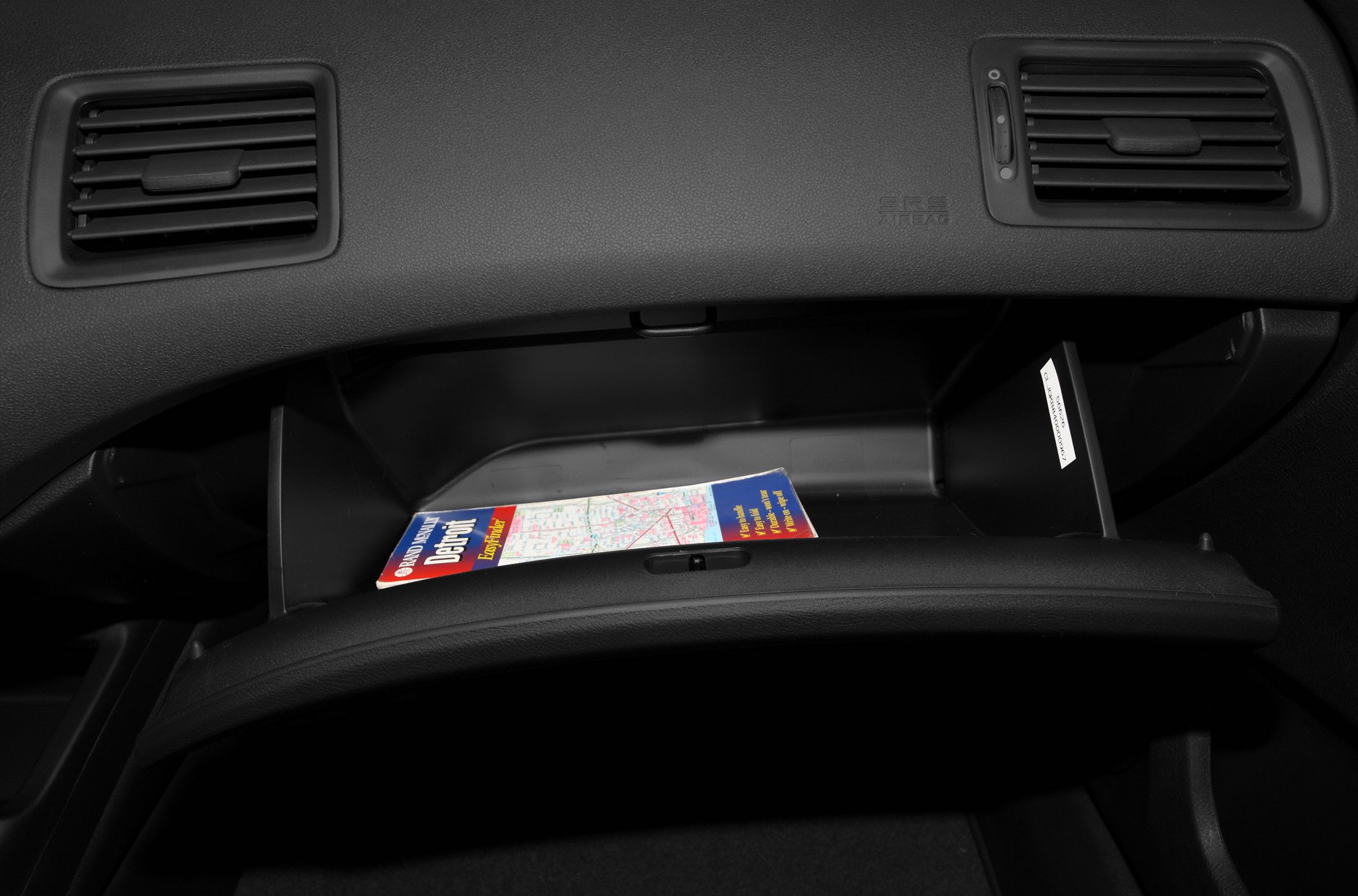 Open glove box with map and dashboard air vents