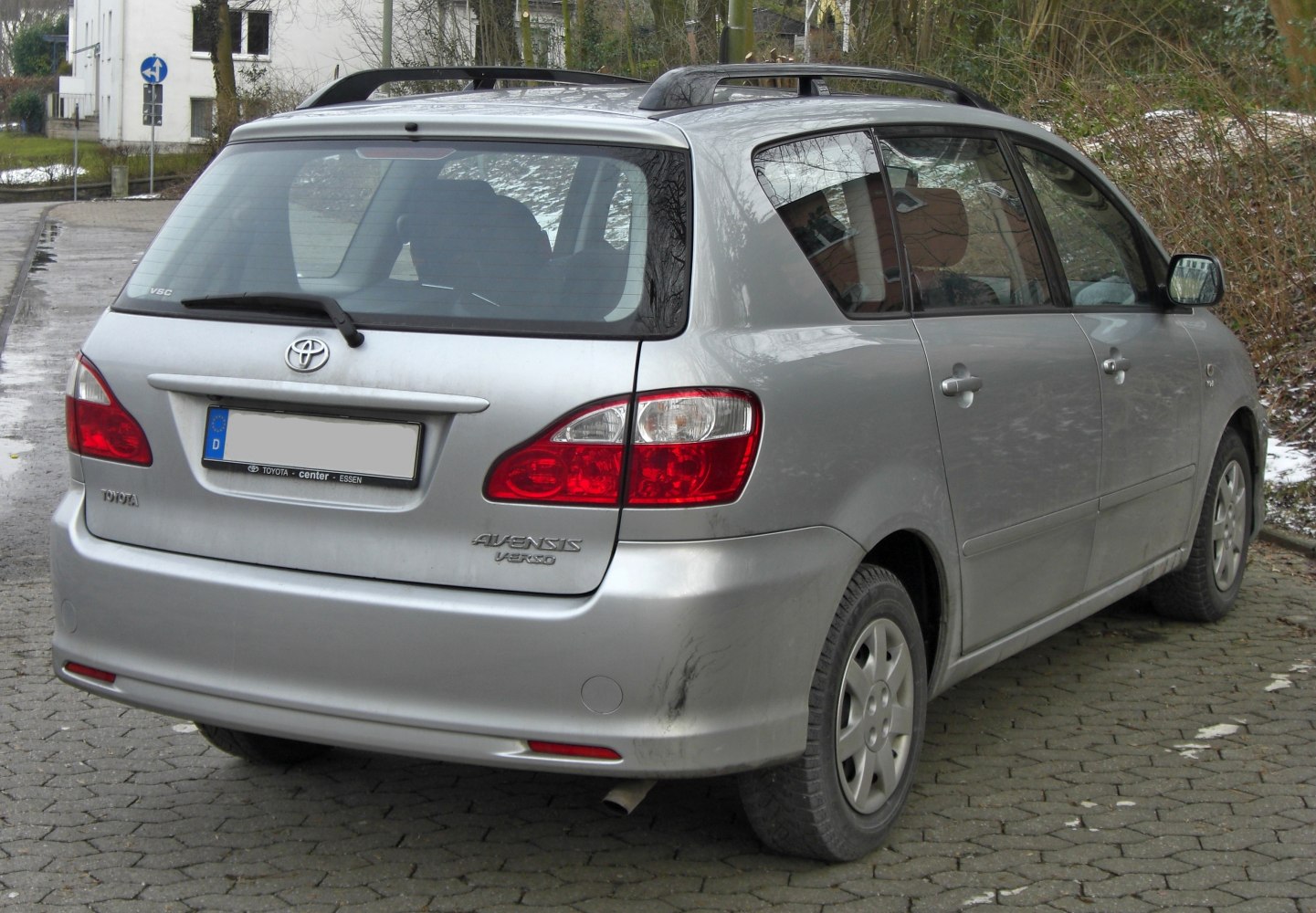 Rear view of a silver minivan with distinctive taillights and roof rails