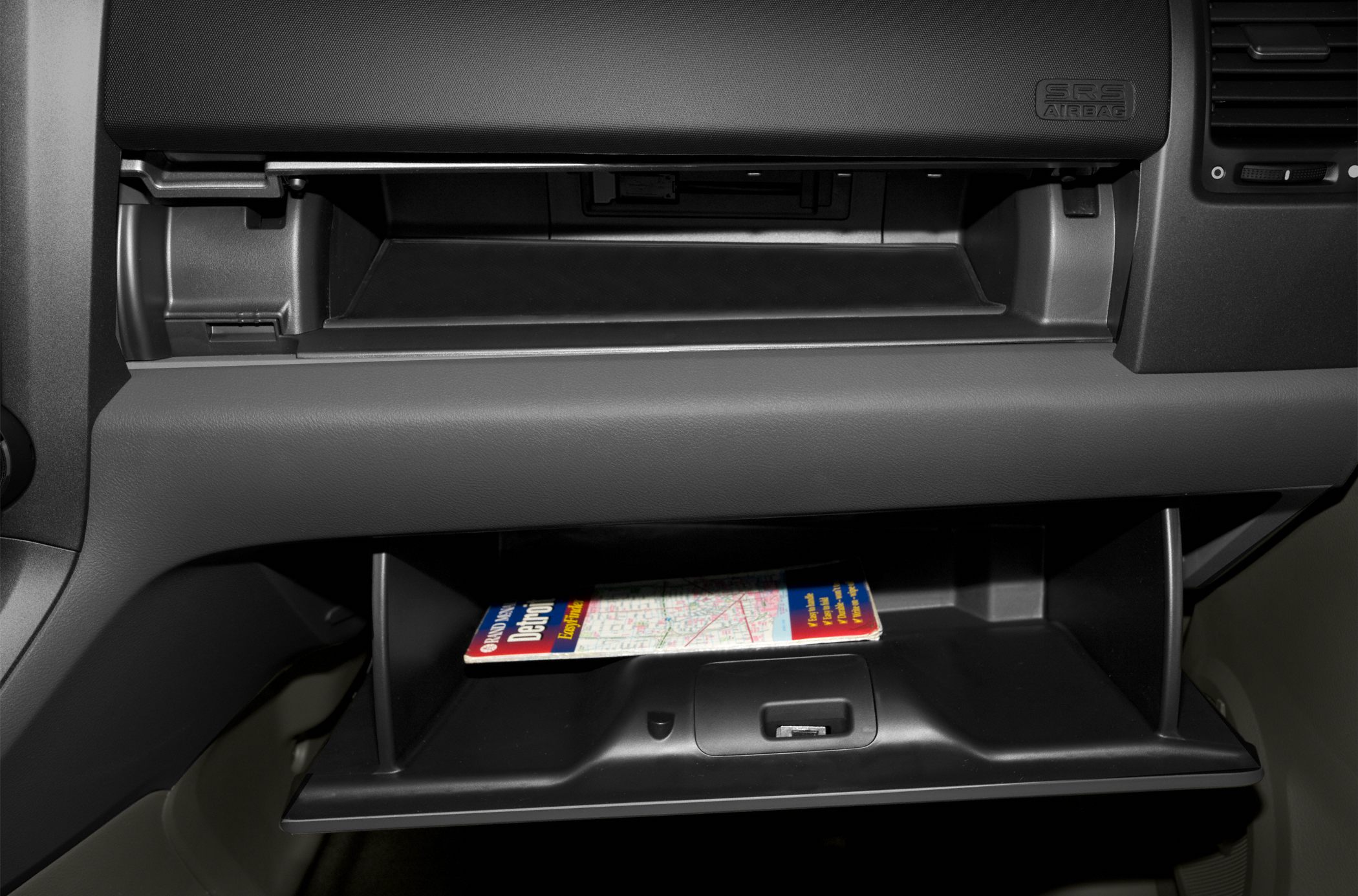 Two open glove compartments with map inside dashboard.