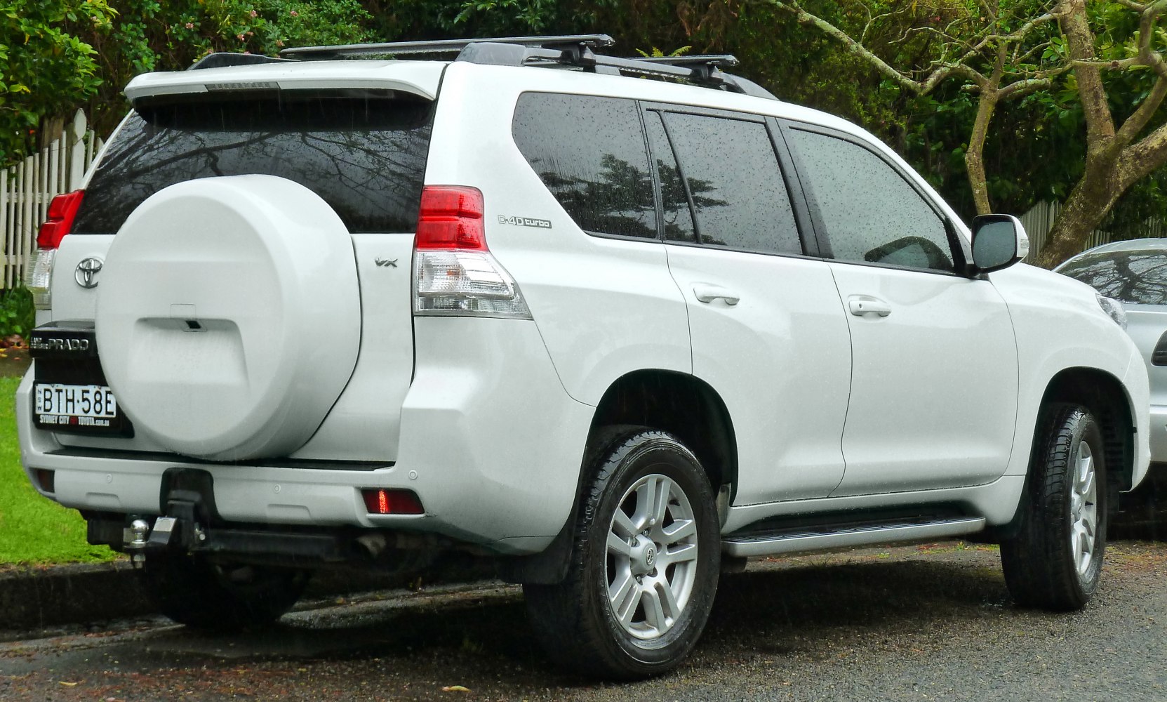 Rear side view of white 5-door SUV with spare tire cover and roof rack
