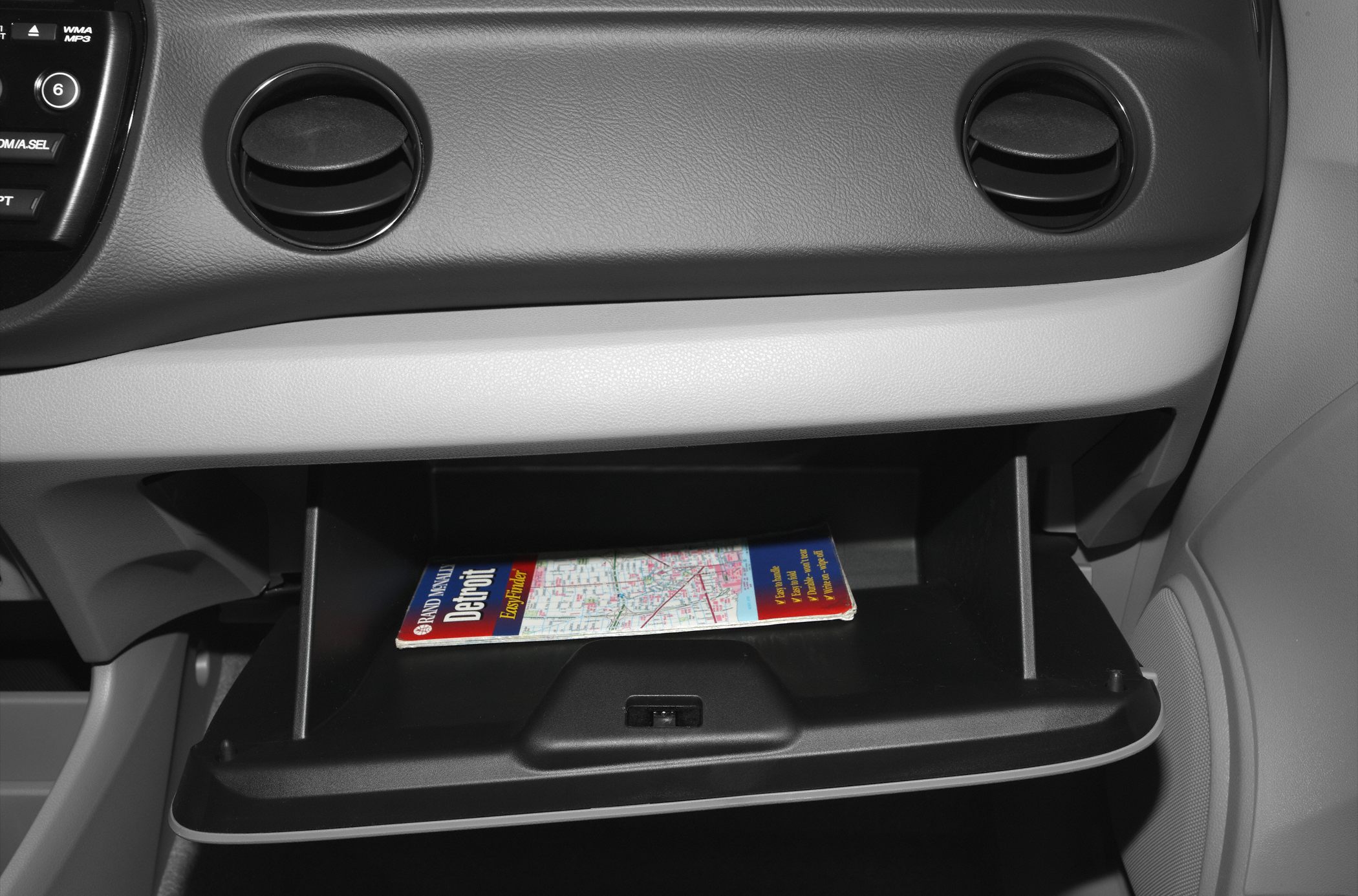 Open glove compartment with map inside dashboard air vents