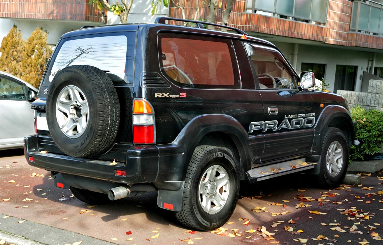 Rear side view of a 3-door SUV with rear-mounted spare tire and rugged design.