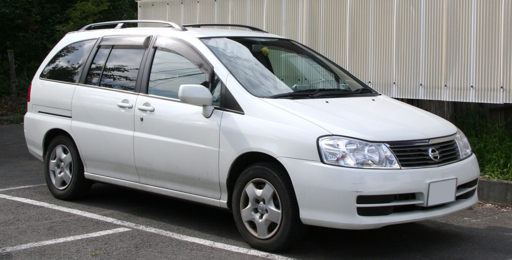 White minivan front side view with roof rails and alloy wheels