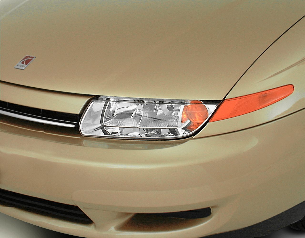 Close-up of headlight and orange side indicator on car front.