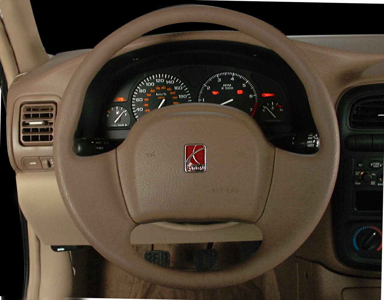 Steering wheel and instrument cluster with gauges and beige dashboard.