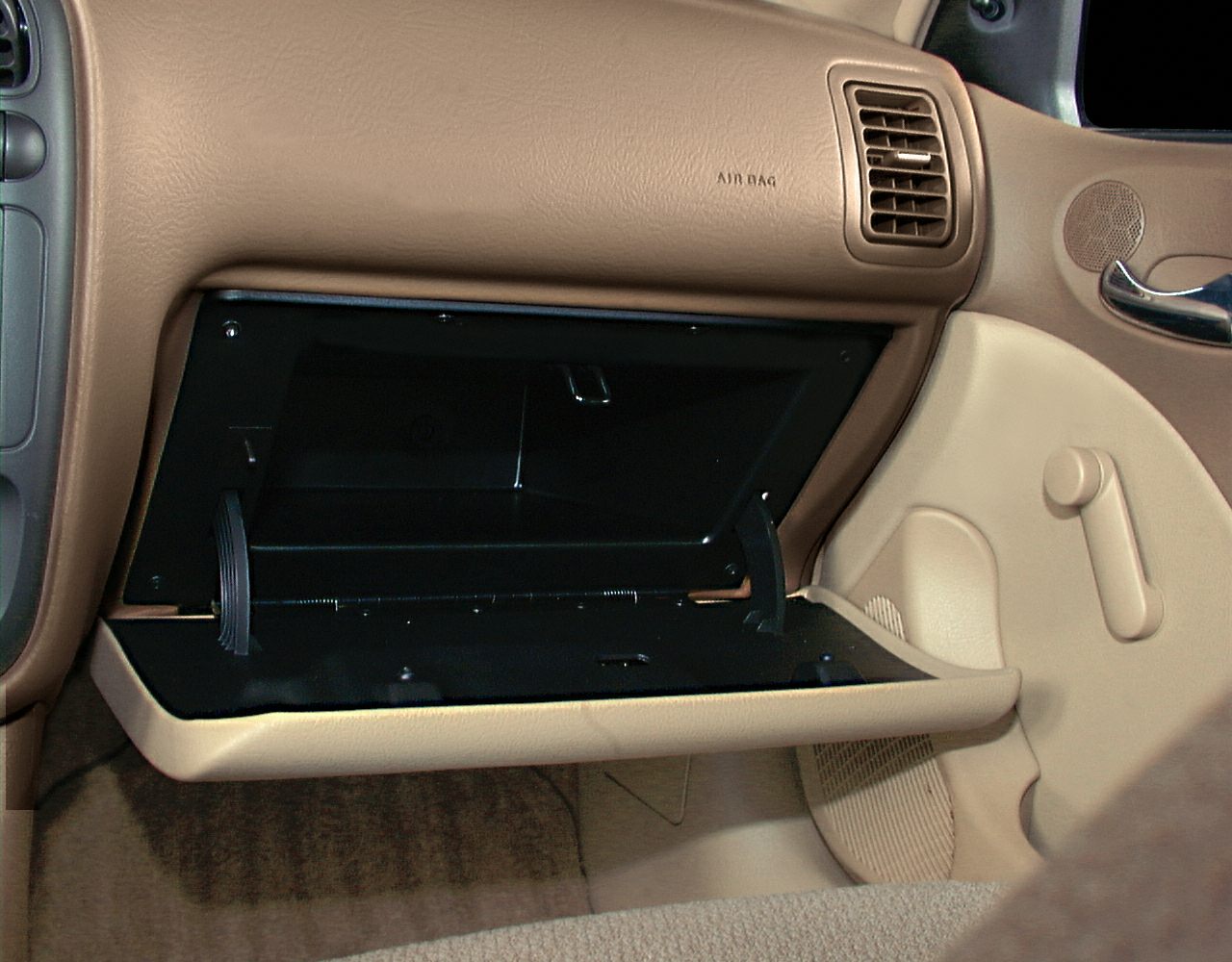 Open glove compartment and passenger side ventilation with beige interior.