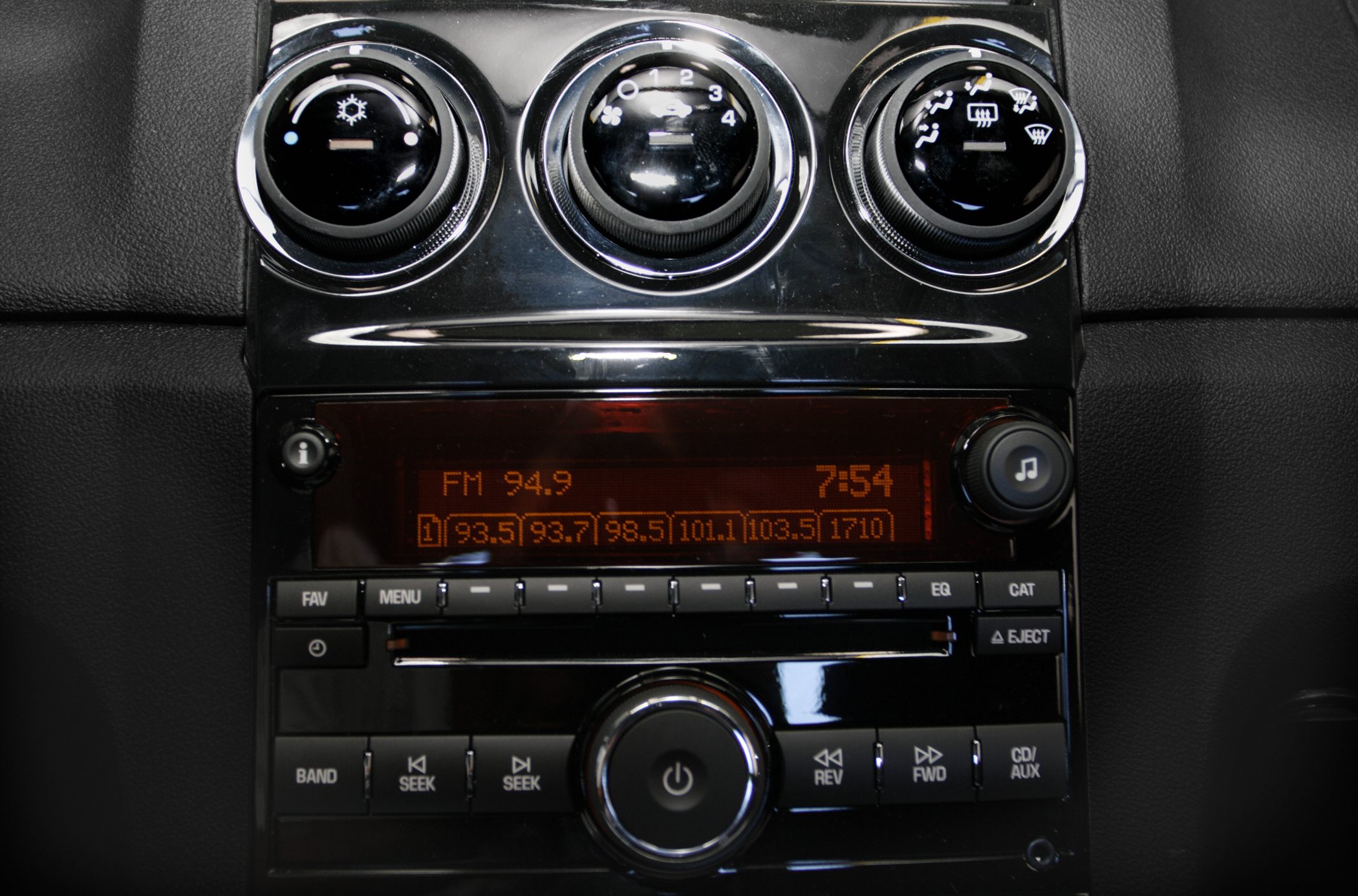 Three climate control knobs and a car stereo system with display and buttons