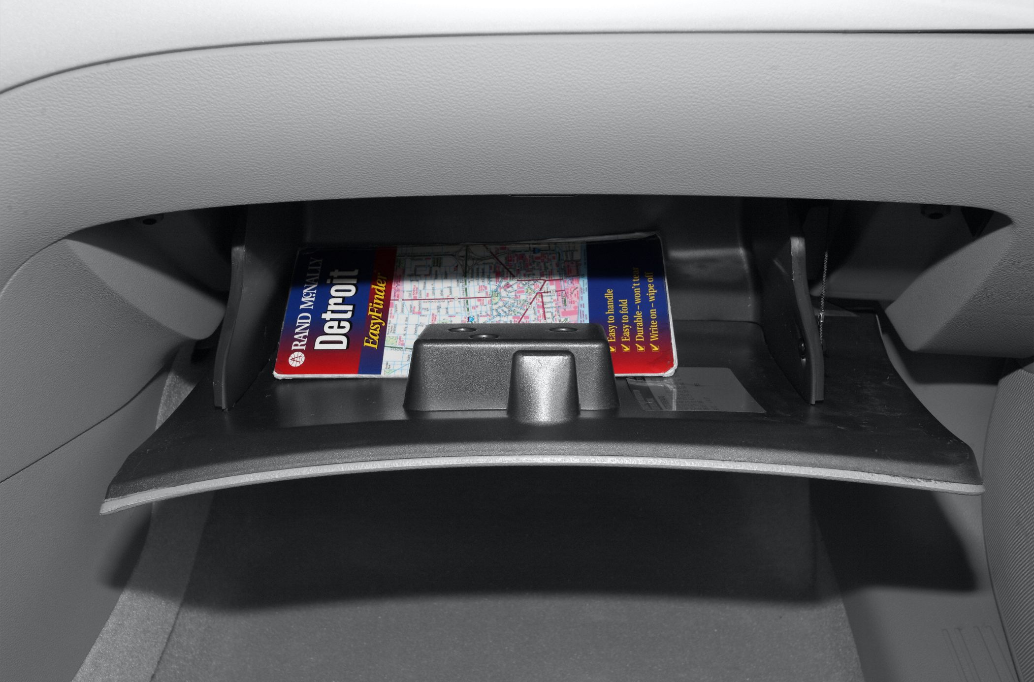 Open glove compartment with a stored city map inside.