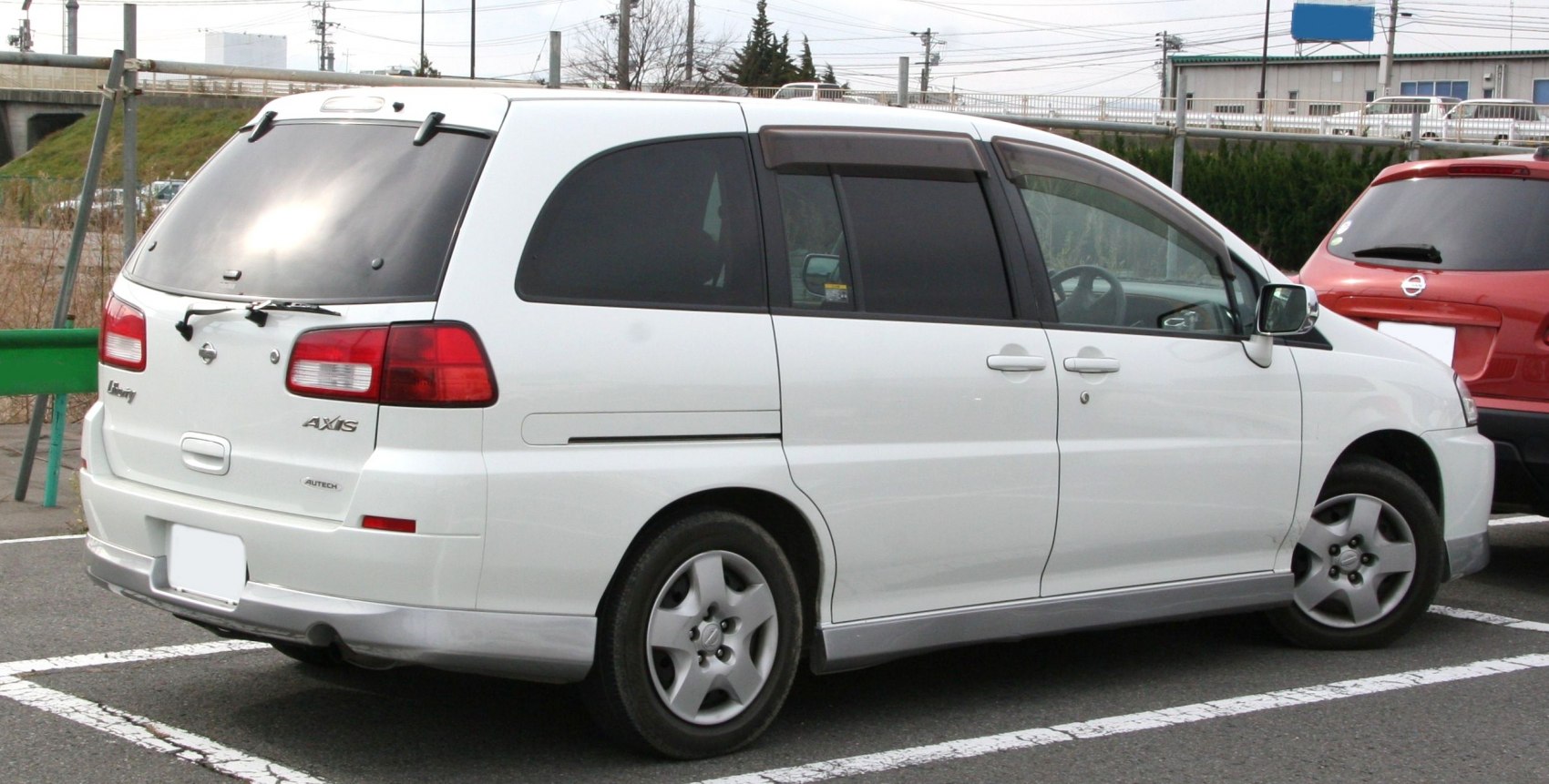 Rear side view of a white minivan with tinted windows and five-spoke alloy wheels