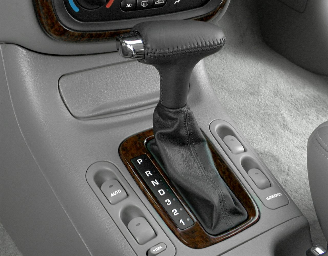 Automatic gear shift lever and power window control buttons on car center console.