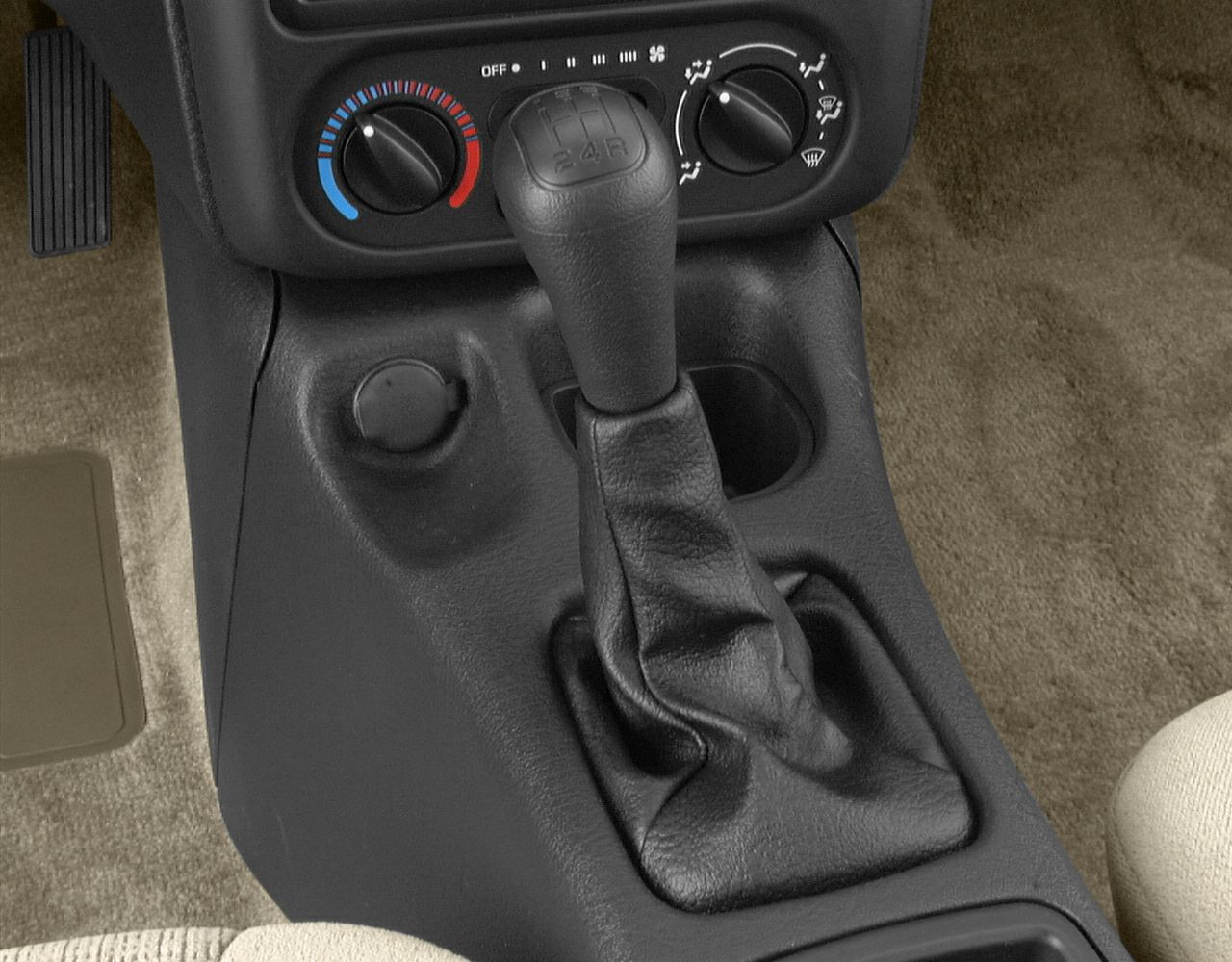 Manual gear shift with leather boot and climate control knobs.