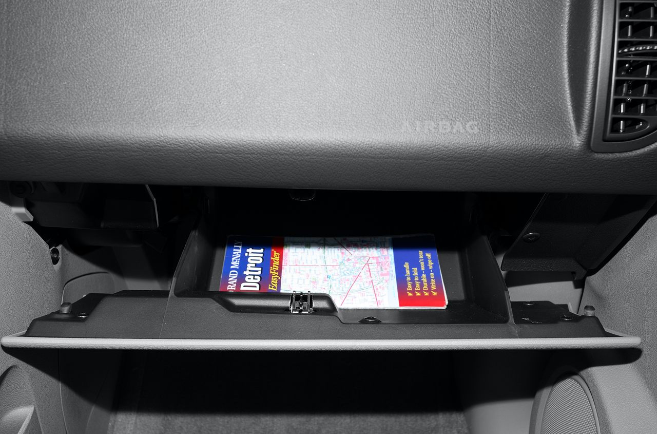 Open glove compartment with road map inside vehicle cabin