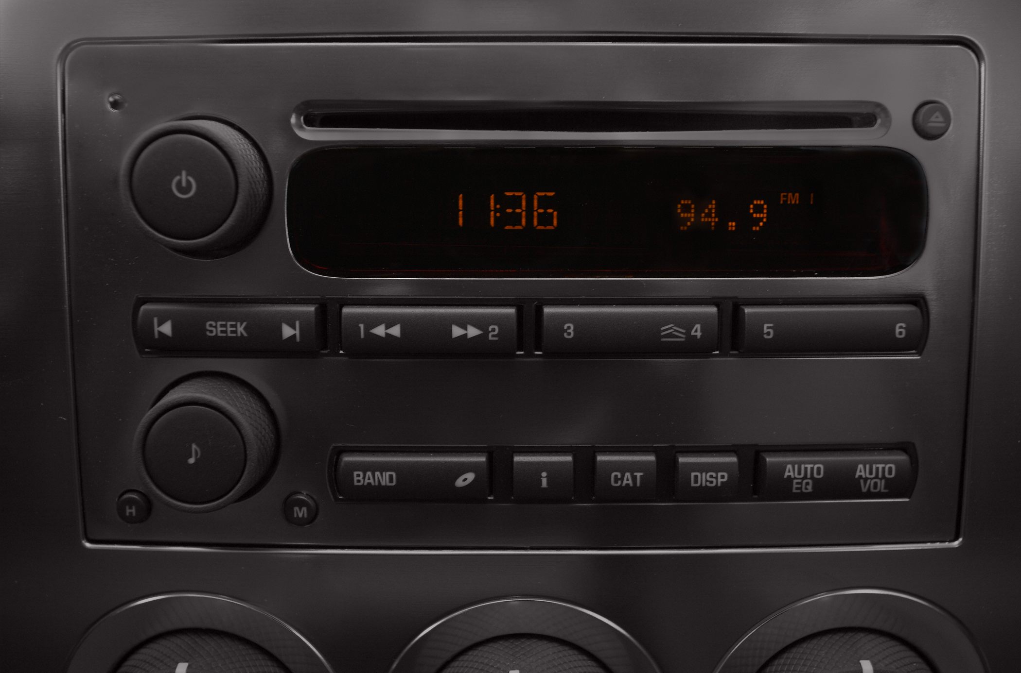 Close-up of car radio control panel with orange digital display and buttons