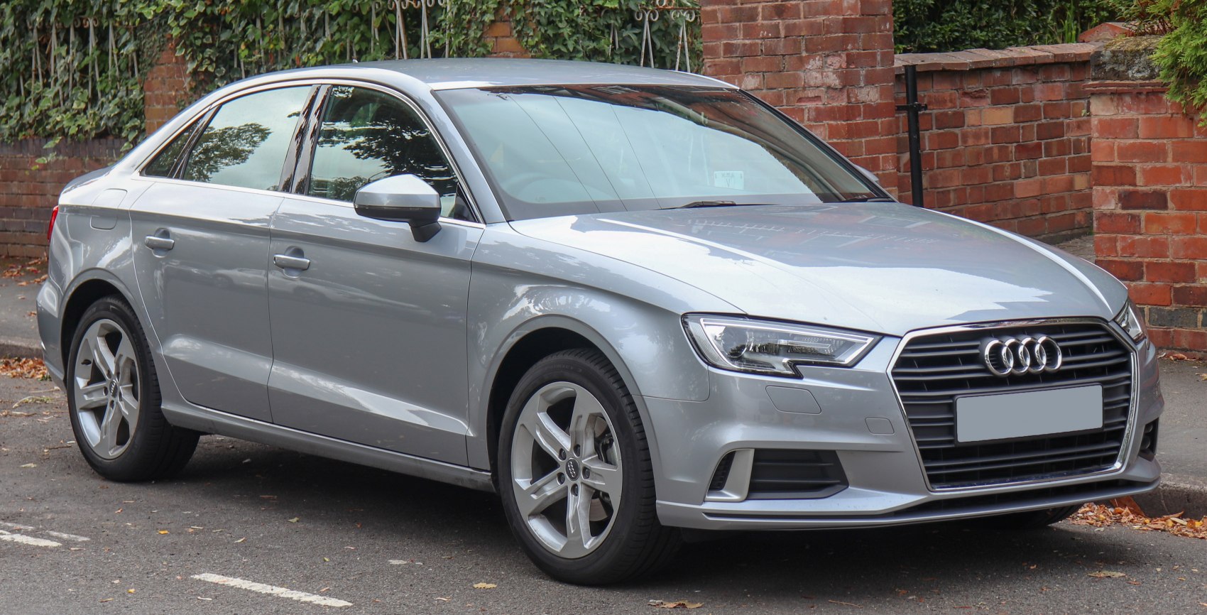 Front and side exterior view of a sedan with modern headlights and alloy wheels.