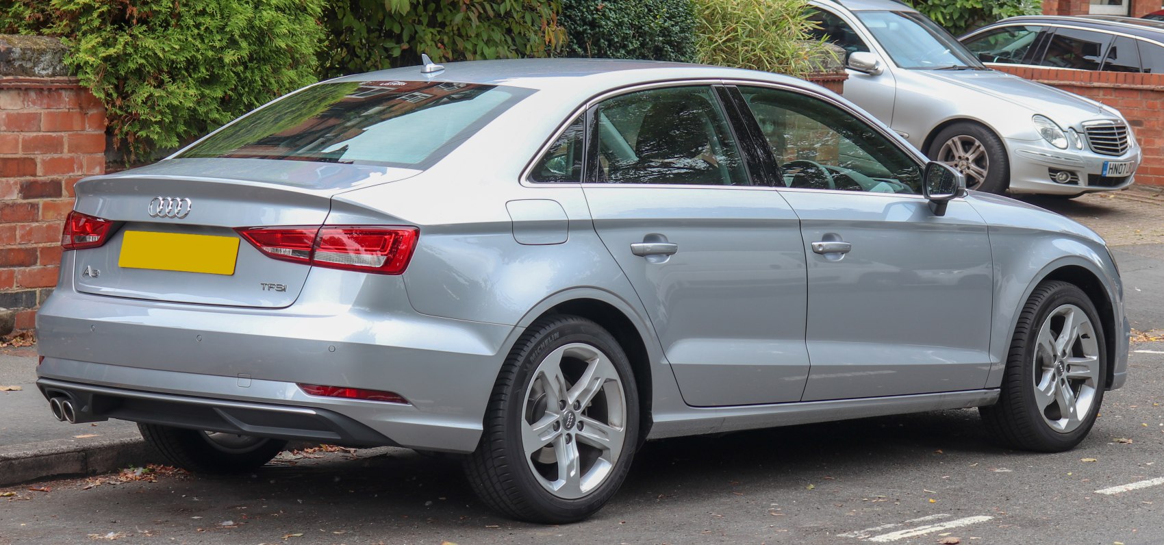 Rear side view of silver sedan with alloy wheels and dual exhaust.