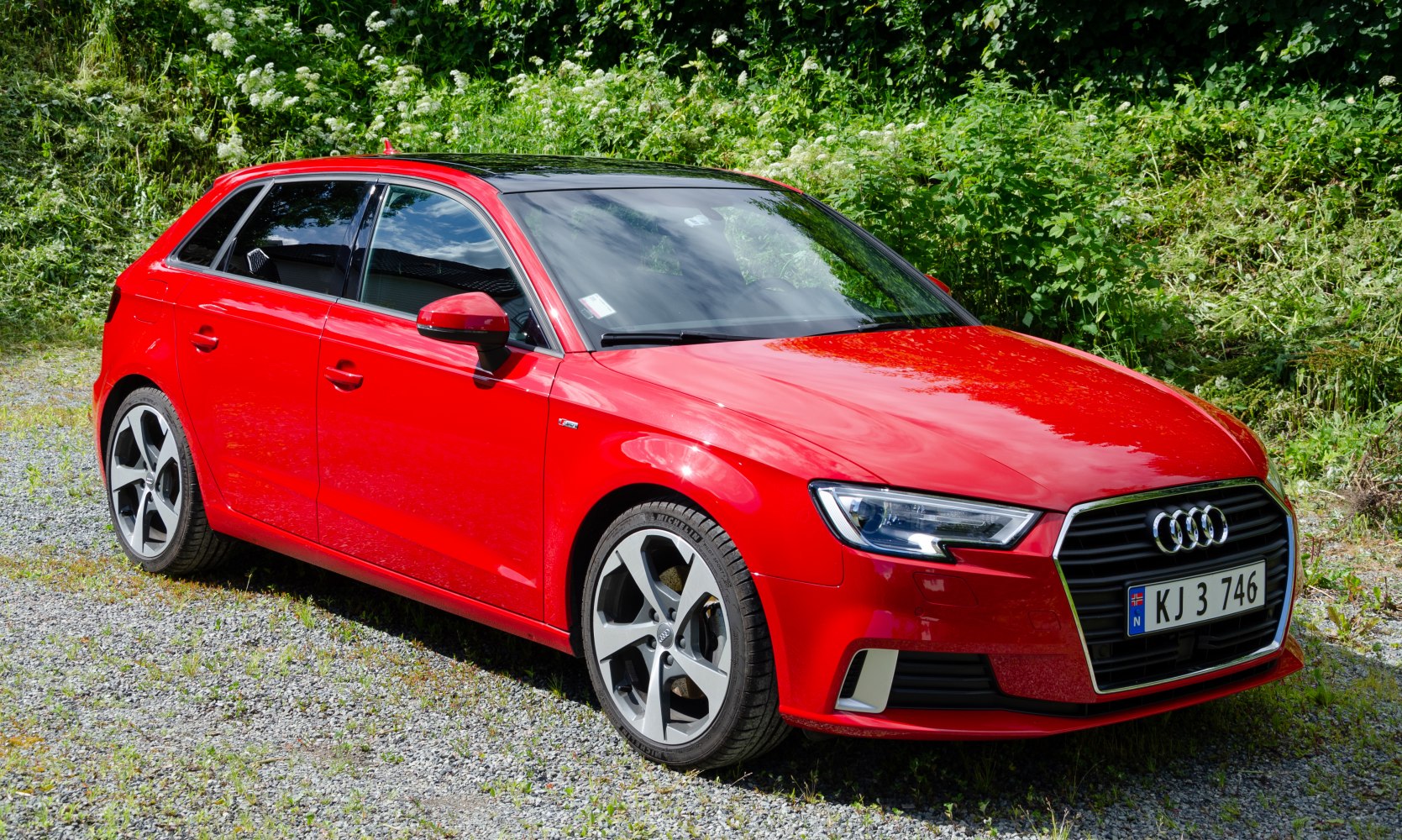 Red compact hatchback with LED headlights and five-spoke alloy wheels
