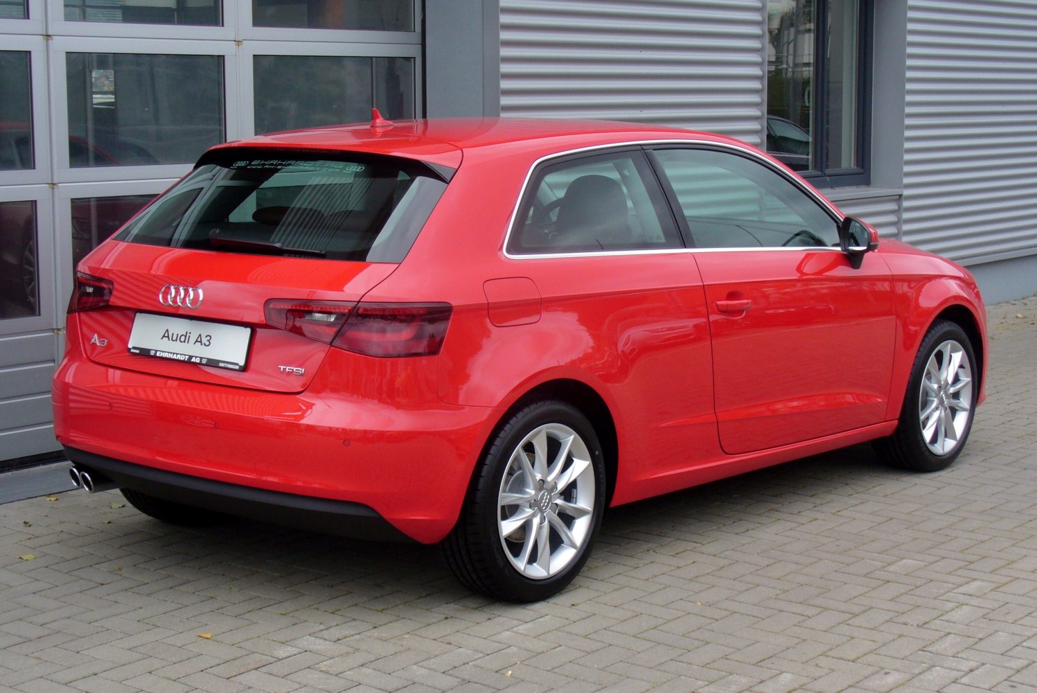 Rear and side view of red hatchback with alloy wheels and dual exhausts