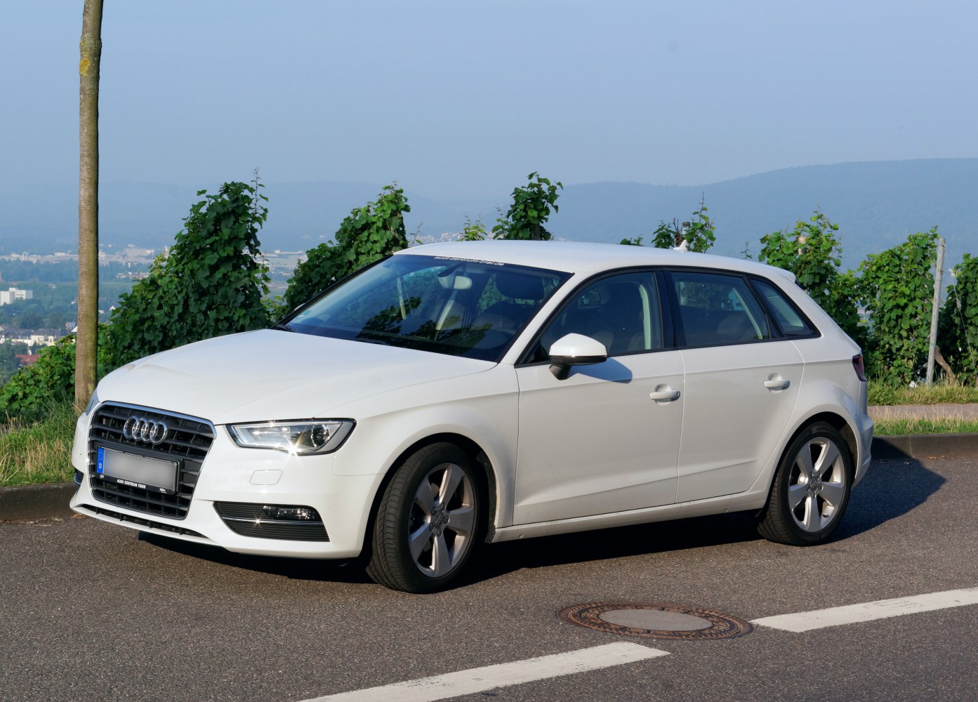 Front side view of a white compact hatchback with five doors and alloy wheels