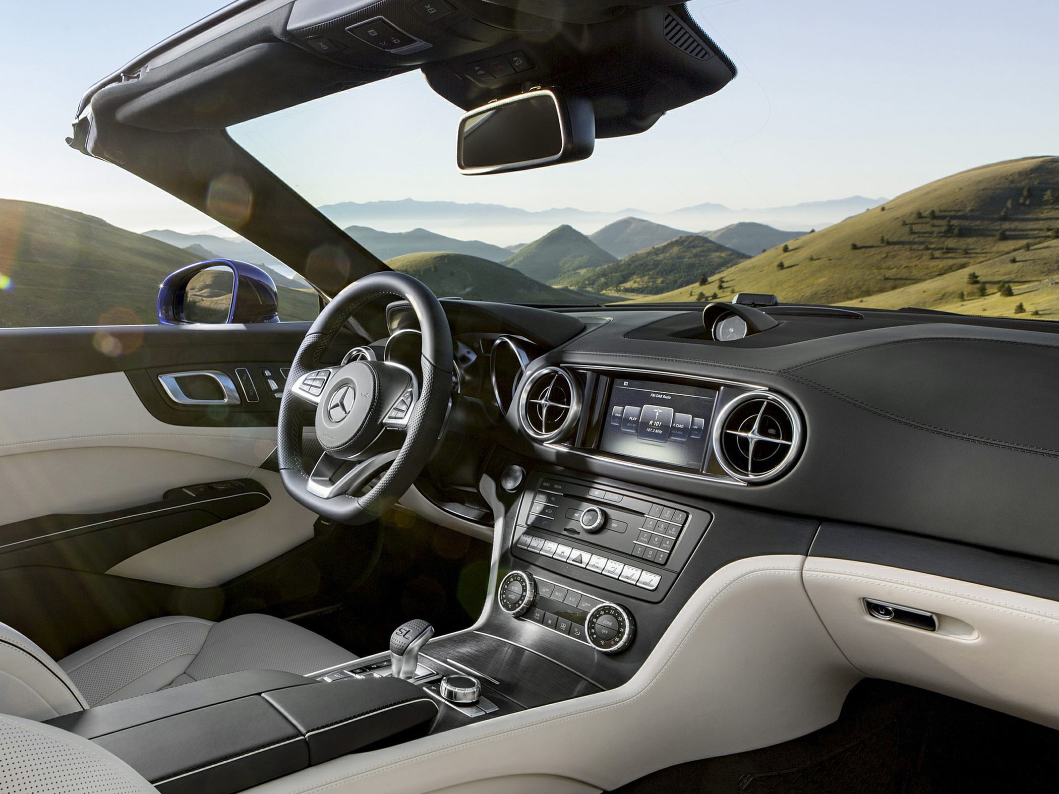 Convertible luxury car interior with advanced dashboard and steering wheel.
