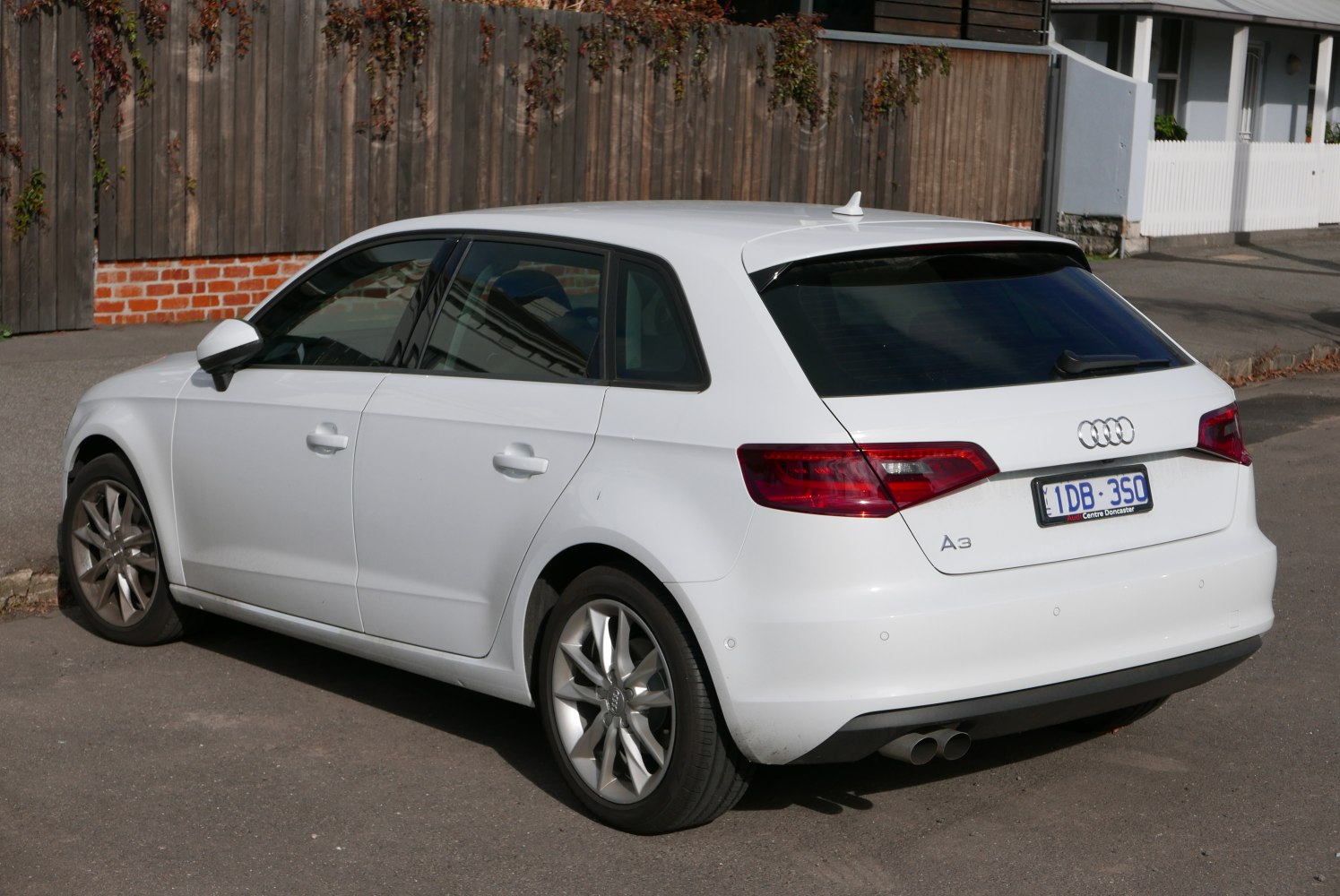 Rear three-quarter view of a white hatchback with dual exhaust and alloy wheels