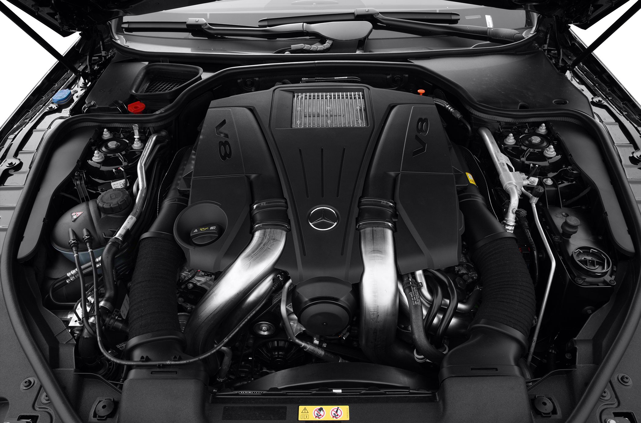 Close-up of a V8 engine with prominent air intake pipes and Mercedes-Benz emblem.