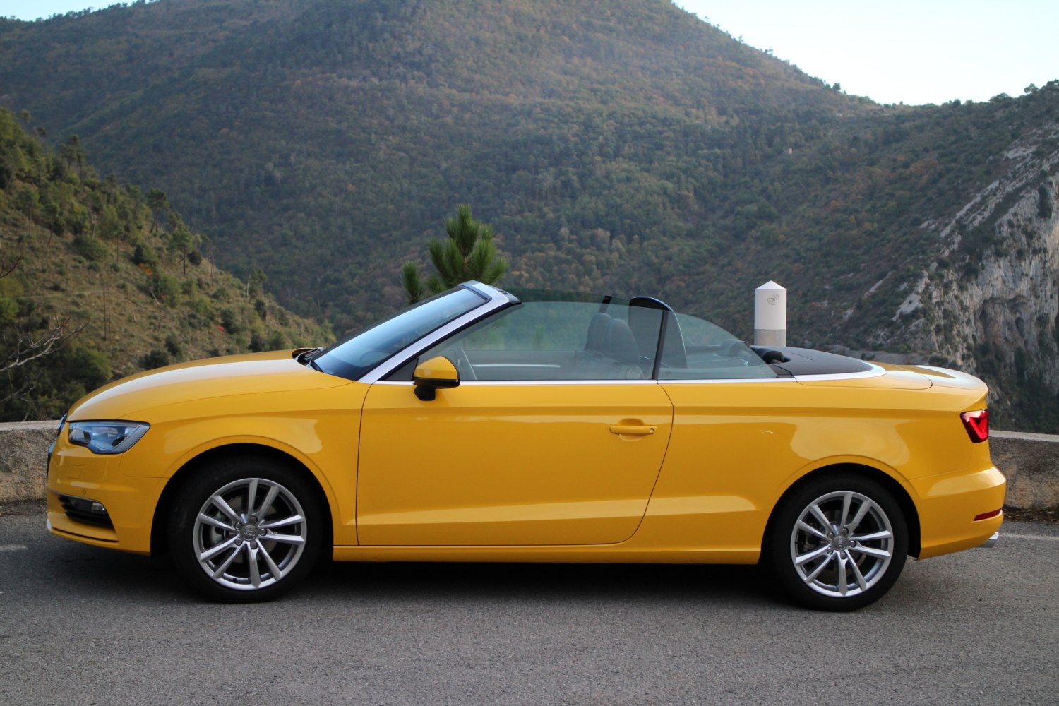 Yellow convertible with lowered soft top roof and alloy wheels
