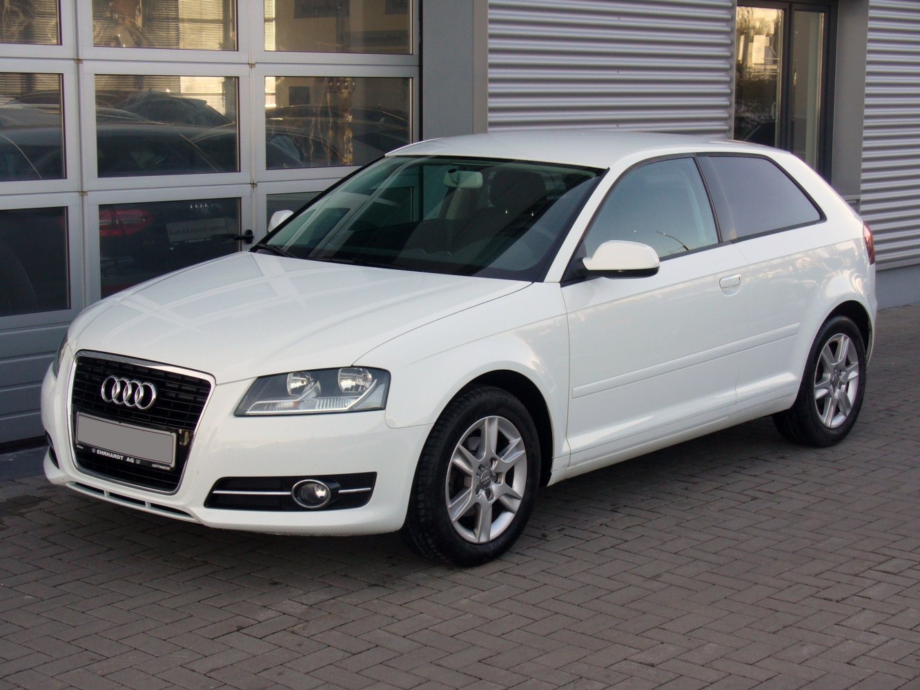 White compact hatchback with front side view and alloy wheels