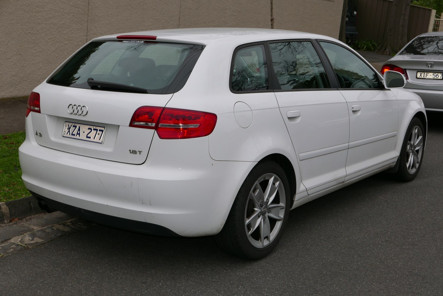 Rear side view of white hatchback with taillights and alloy wheels