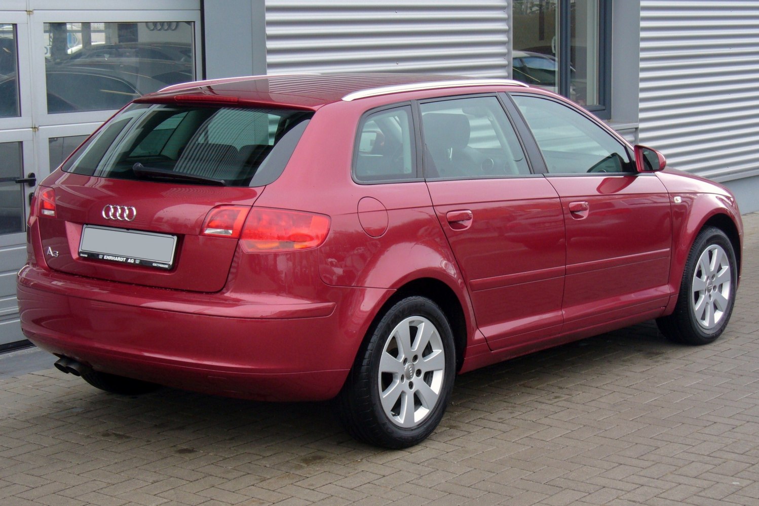 Rear side view of a red hatchback with alloy wheels and prominent tail lights