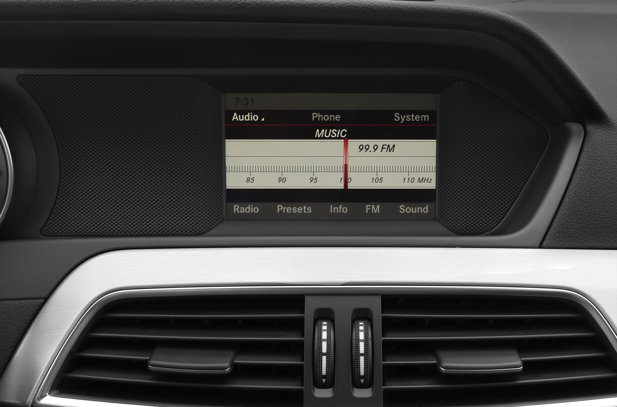 Close-up of car radio FM display and central air vents.