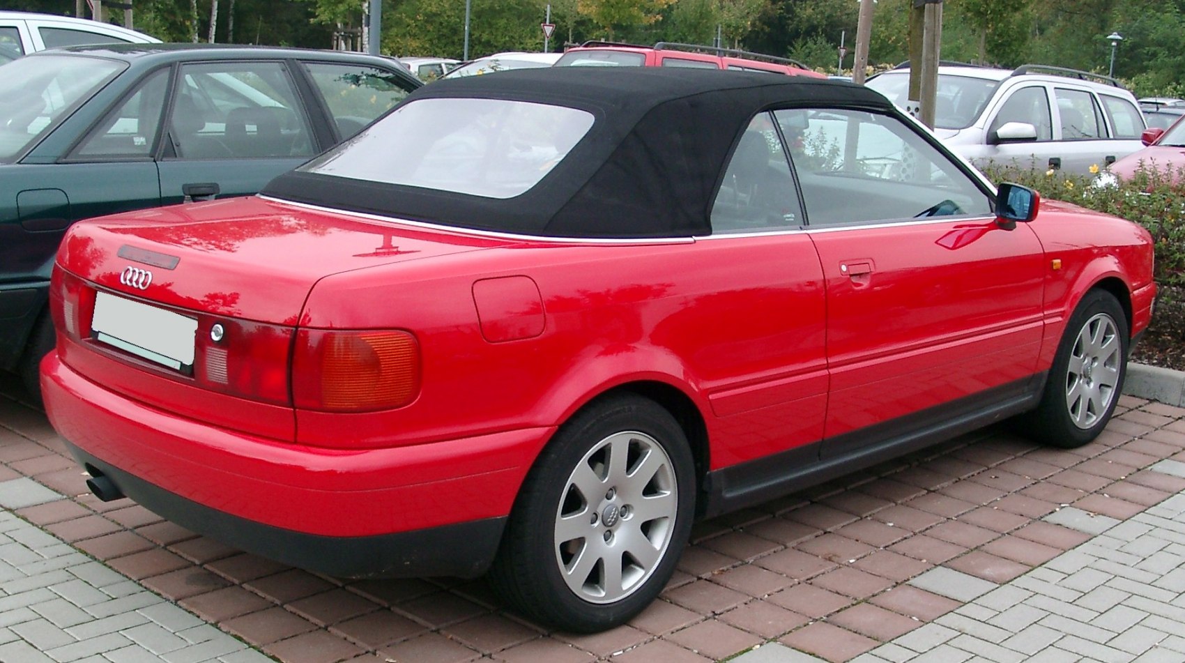 Red coupe convertible with black fabric soft top and alloy wheels