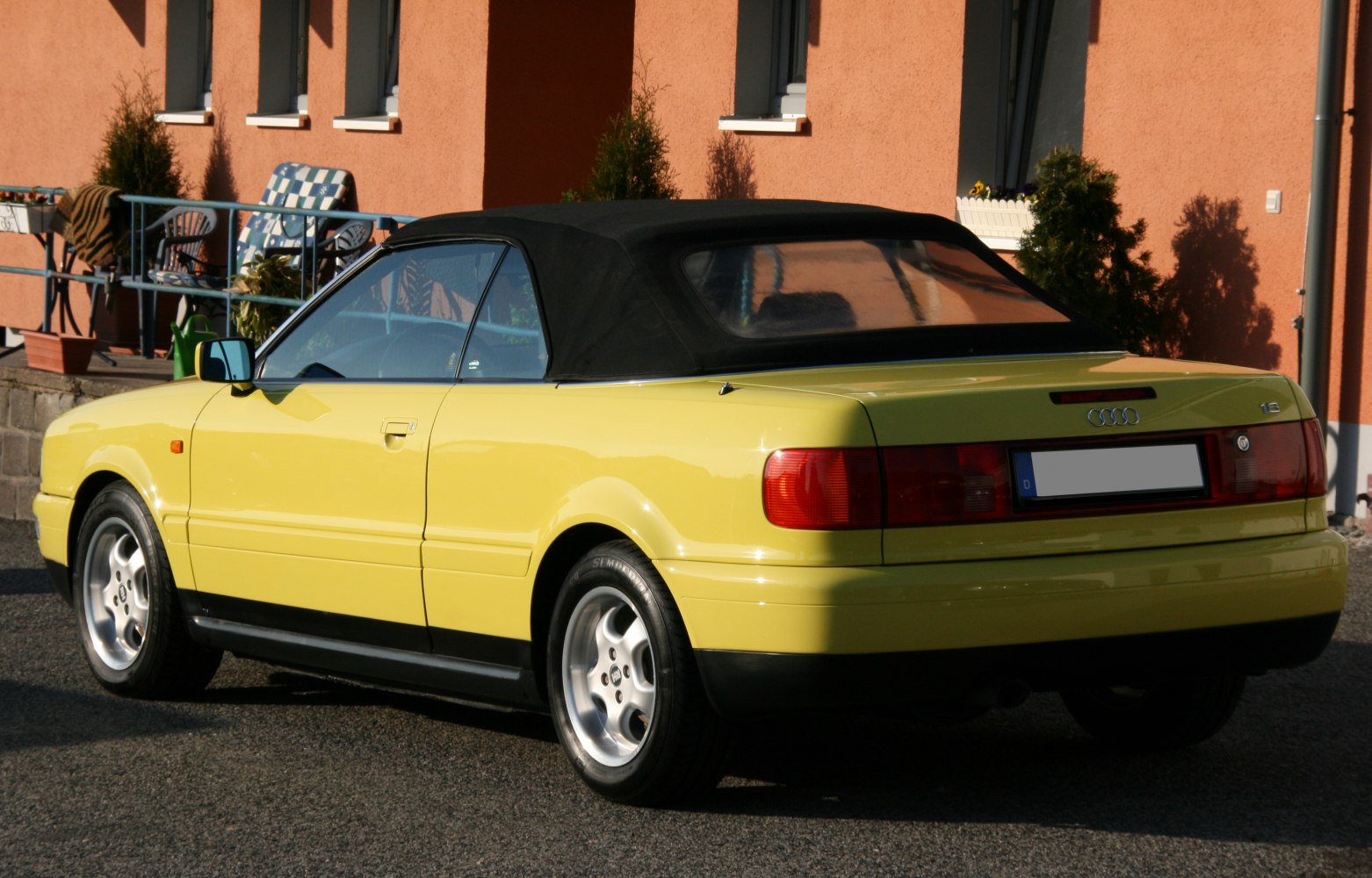 Yellow convertible with black soft top and alloy wheels