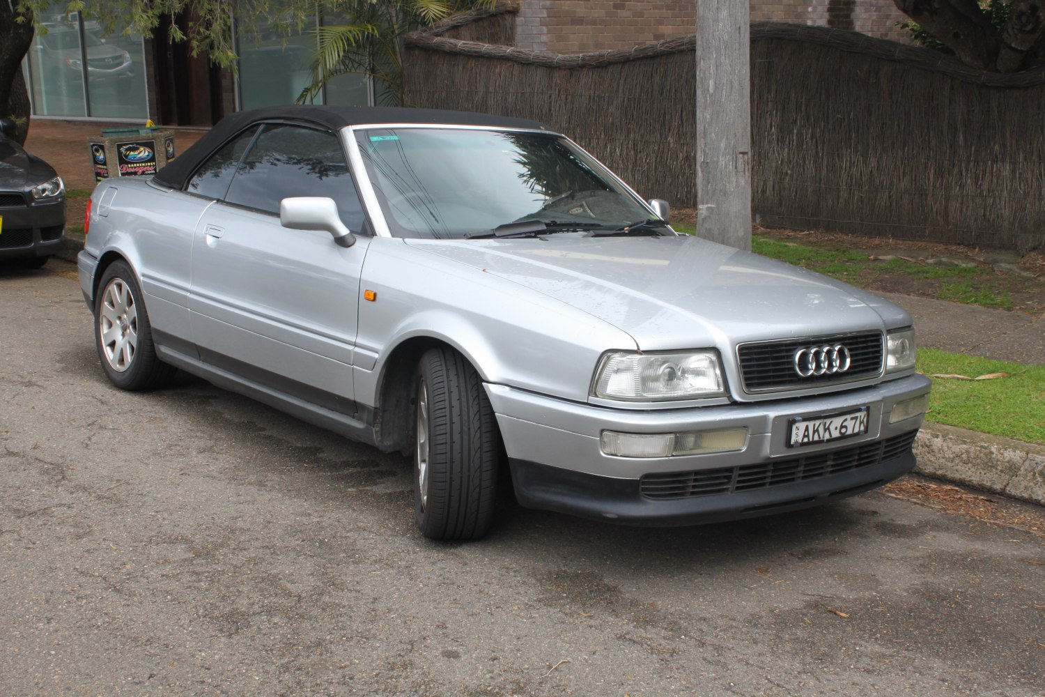 Silver convertible with black soft top and classic front grille.