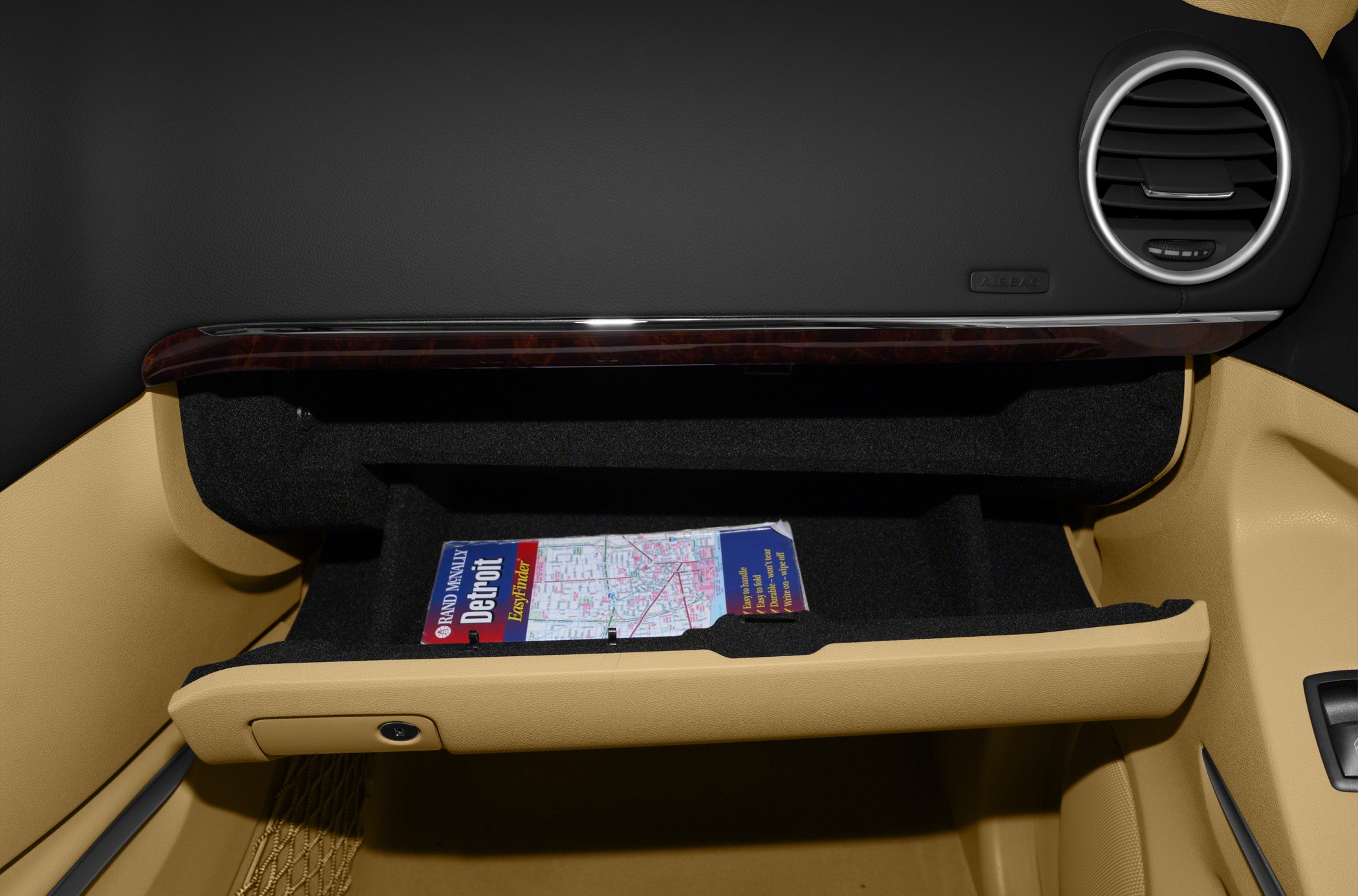 Open glove compartment with beige interior and round air vent