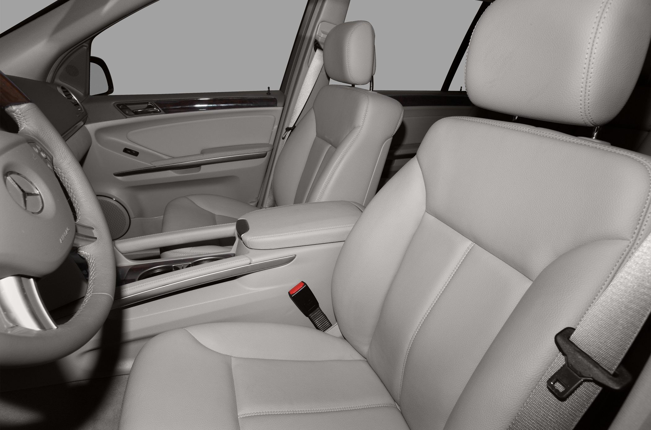 Luxury leather front seats and wood trim interior with steering wheel and seatbelt