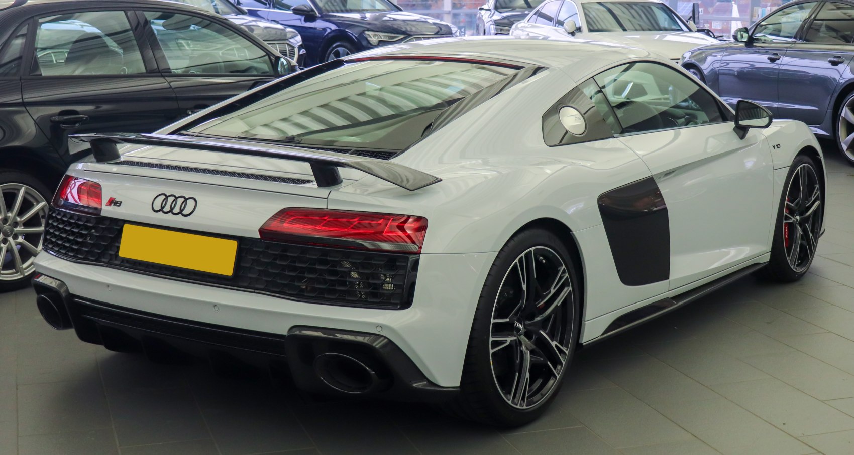 Rear-side view with spoiler, LED taillights, black air intake, and alloy wheels