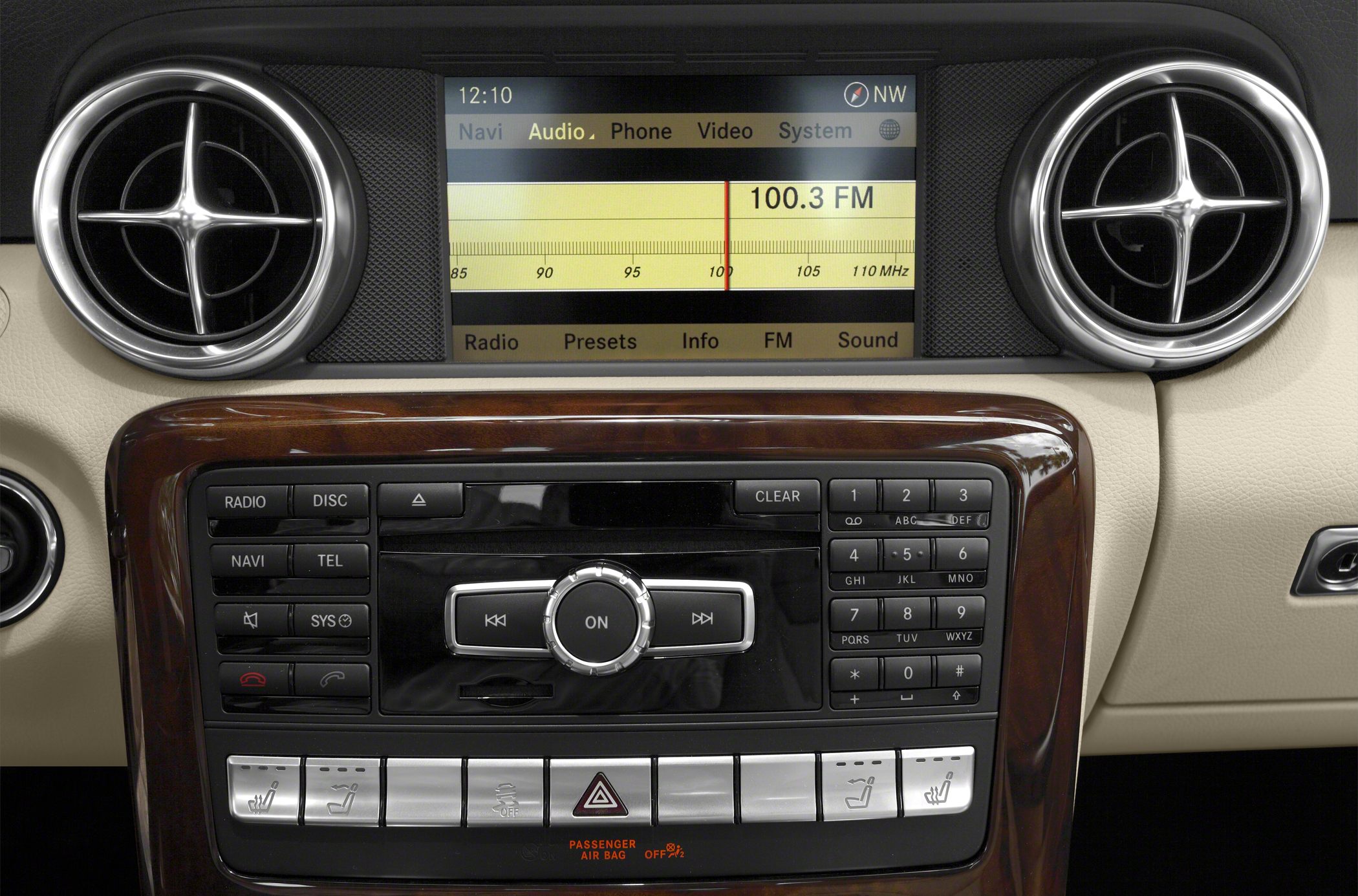 Car interior infotainment system with round air vents and wood trim
