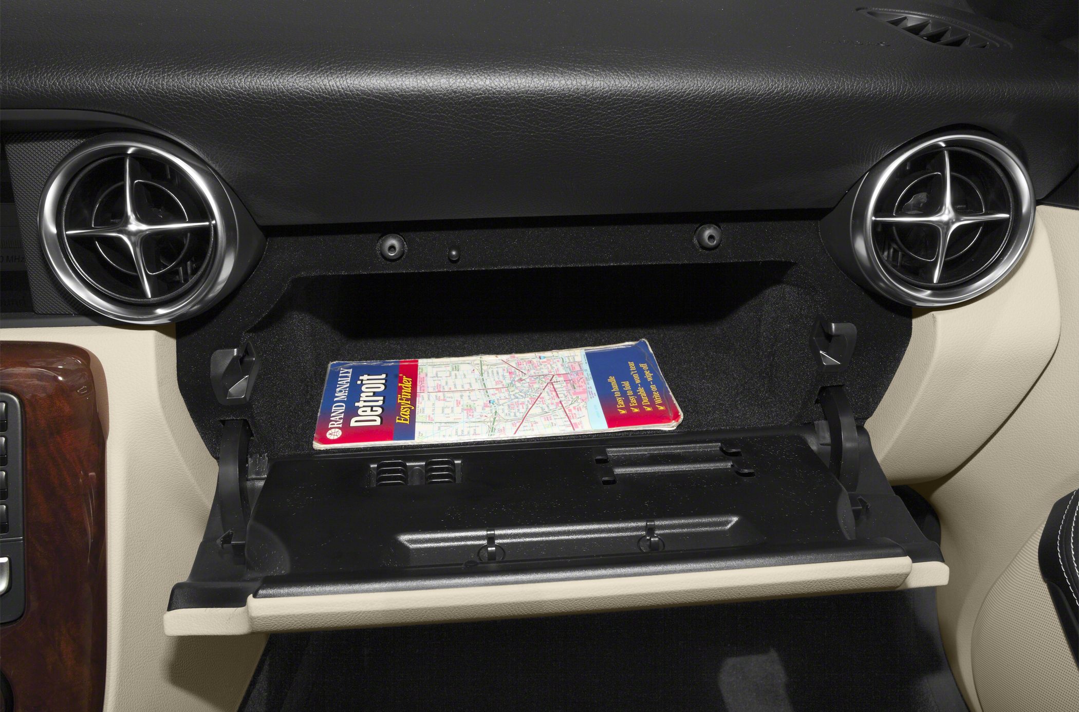 Open glove compartment with twin round air vents on beige-black interior