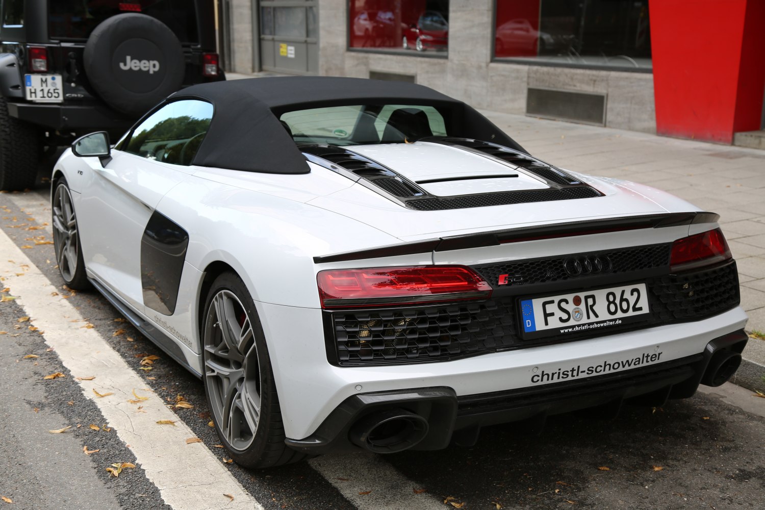 Rear and side view of white convertible with black soft top and distinctive tail lights