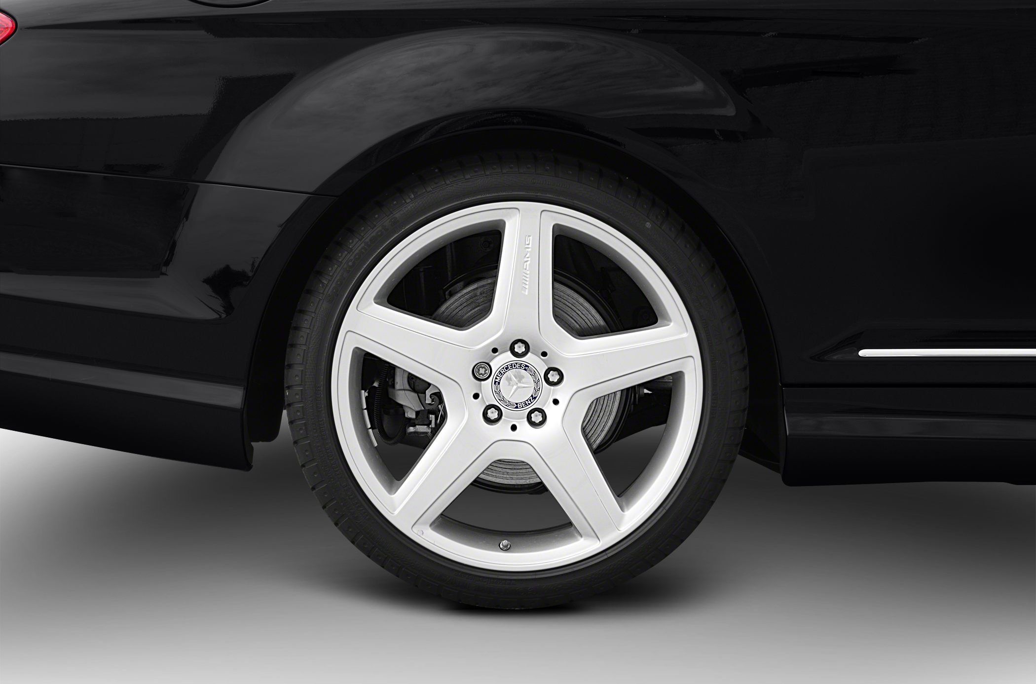 Silver five-spoke AMG alloy wheel with brake disc on rear side.