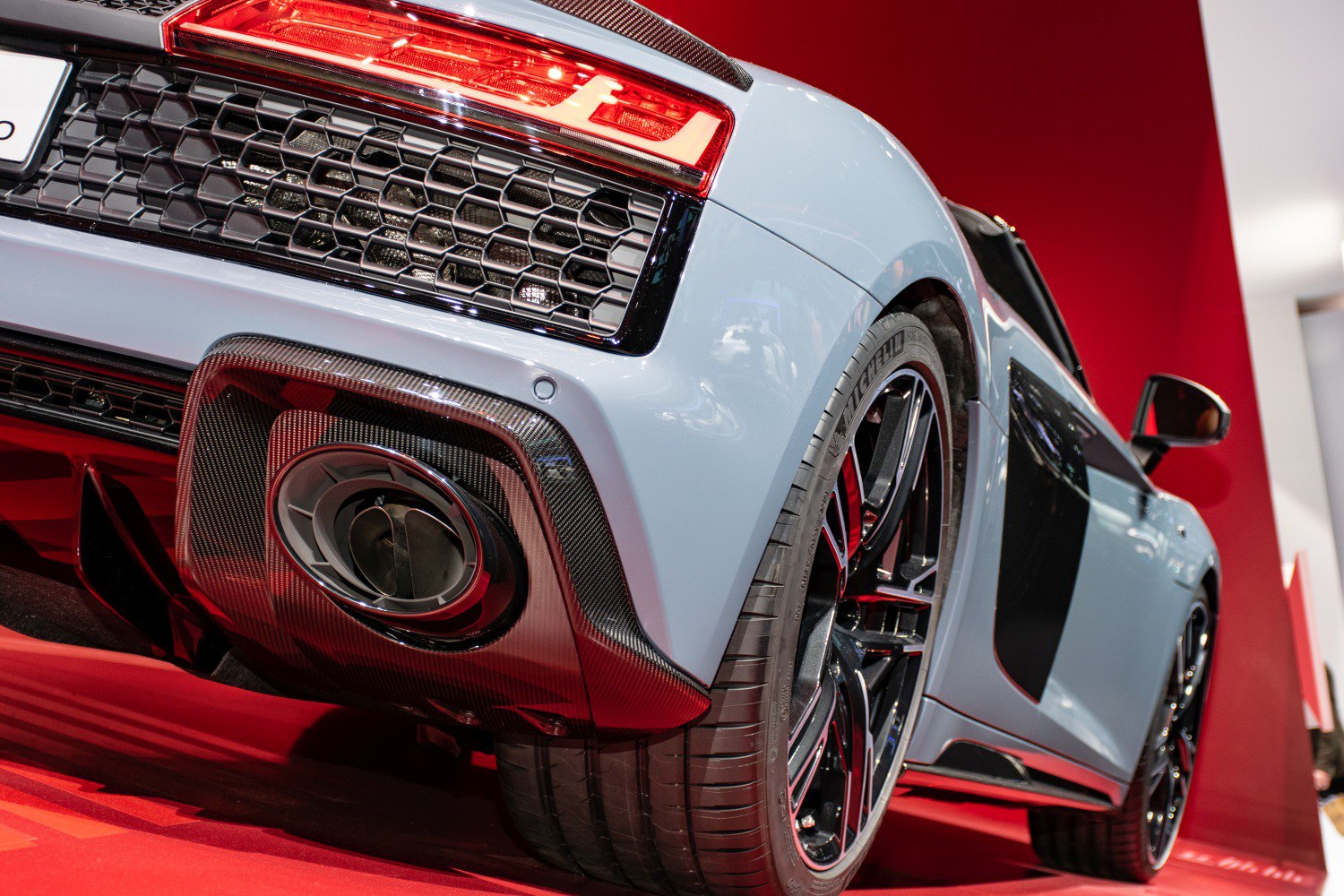 Close-up of rear exhaust, diffuser, honeycomb grille, and wheel