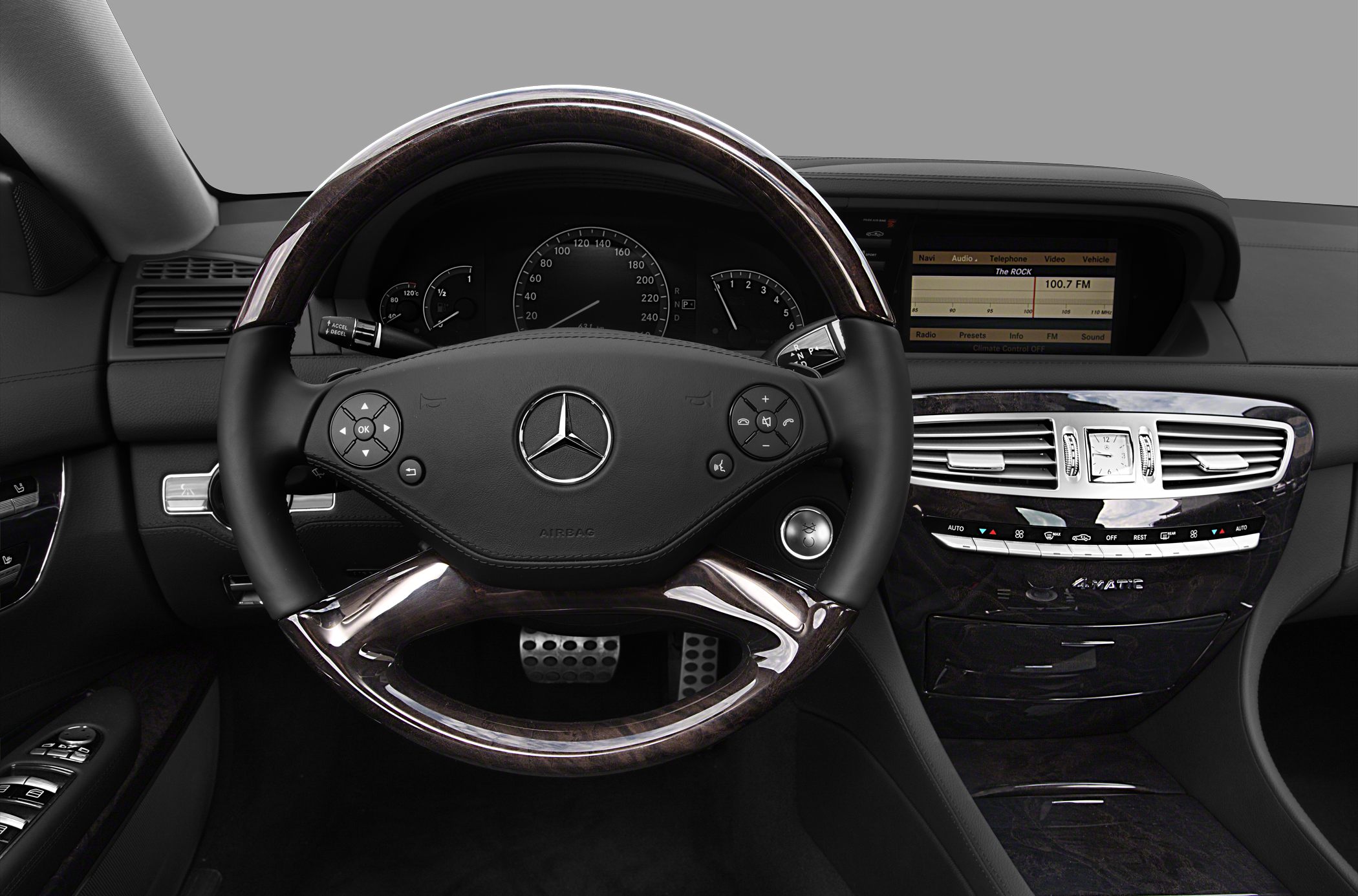 Wood-trimmed steering wheel and luxury dashboard with infotainment controls