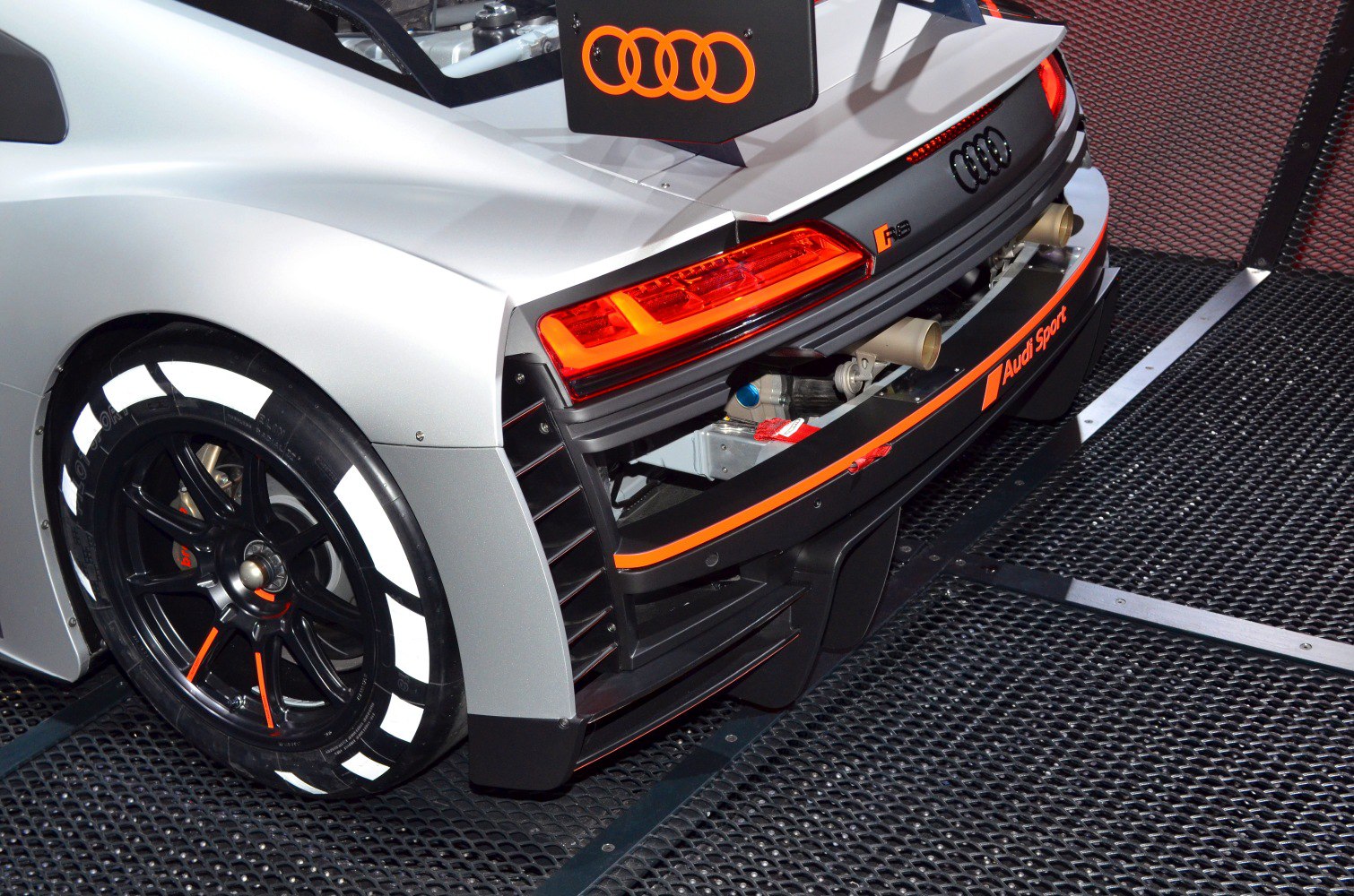 Race car rear end with taillights, racing wheel, and aerodynamic elements