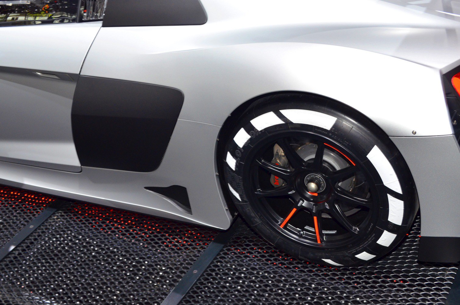 Rear black alloy wheel with white marked racing tire and black side air intake panel