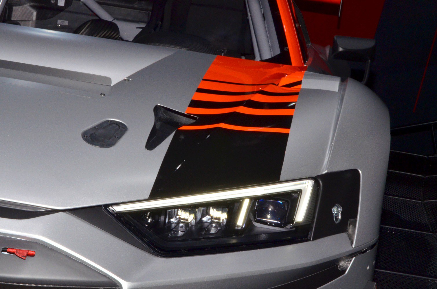 Close-up of sharp headlight and aerodynamic racing hood with vents