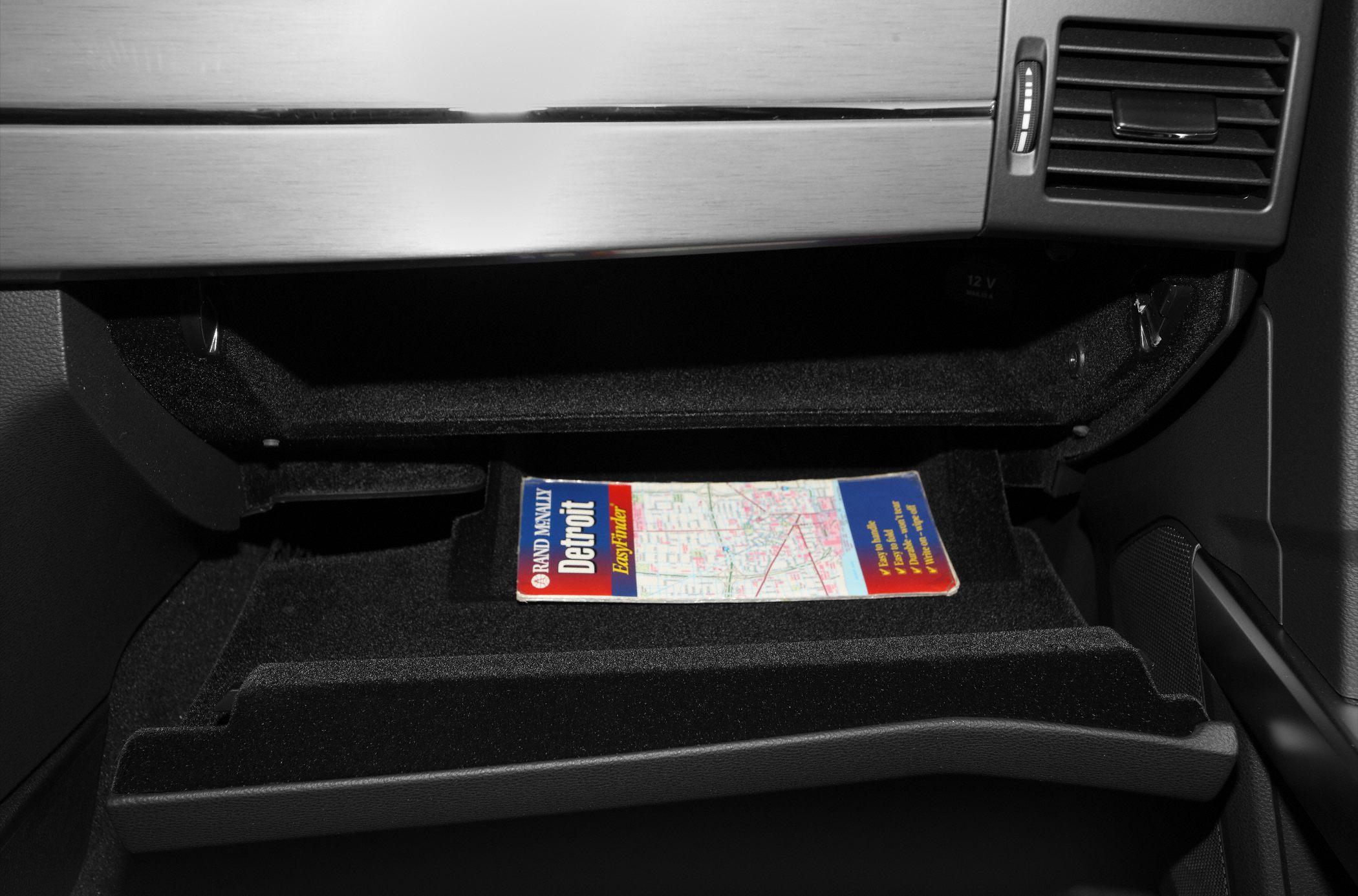 Open glove compartment with Detroit map inside.
