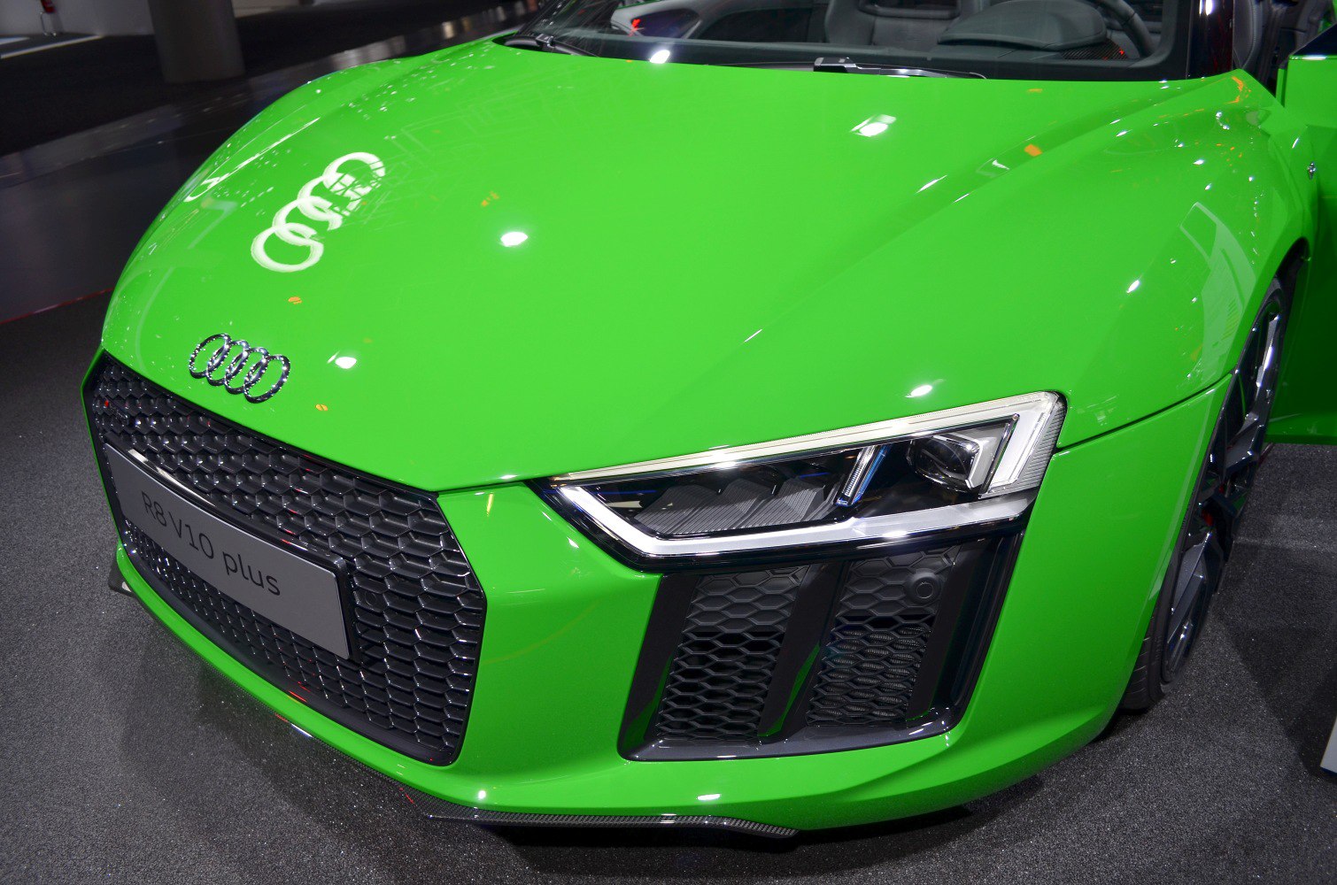 Close-up of green car’s front grille and LED headlight.