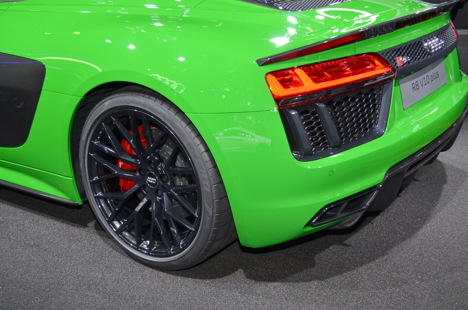 Black alloy rear wheel with red brake caliper and LED taillight on green sports car